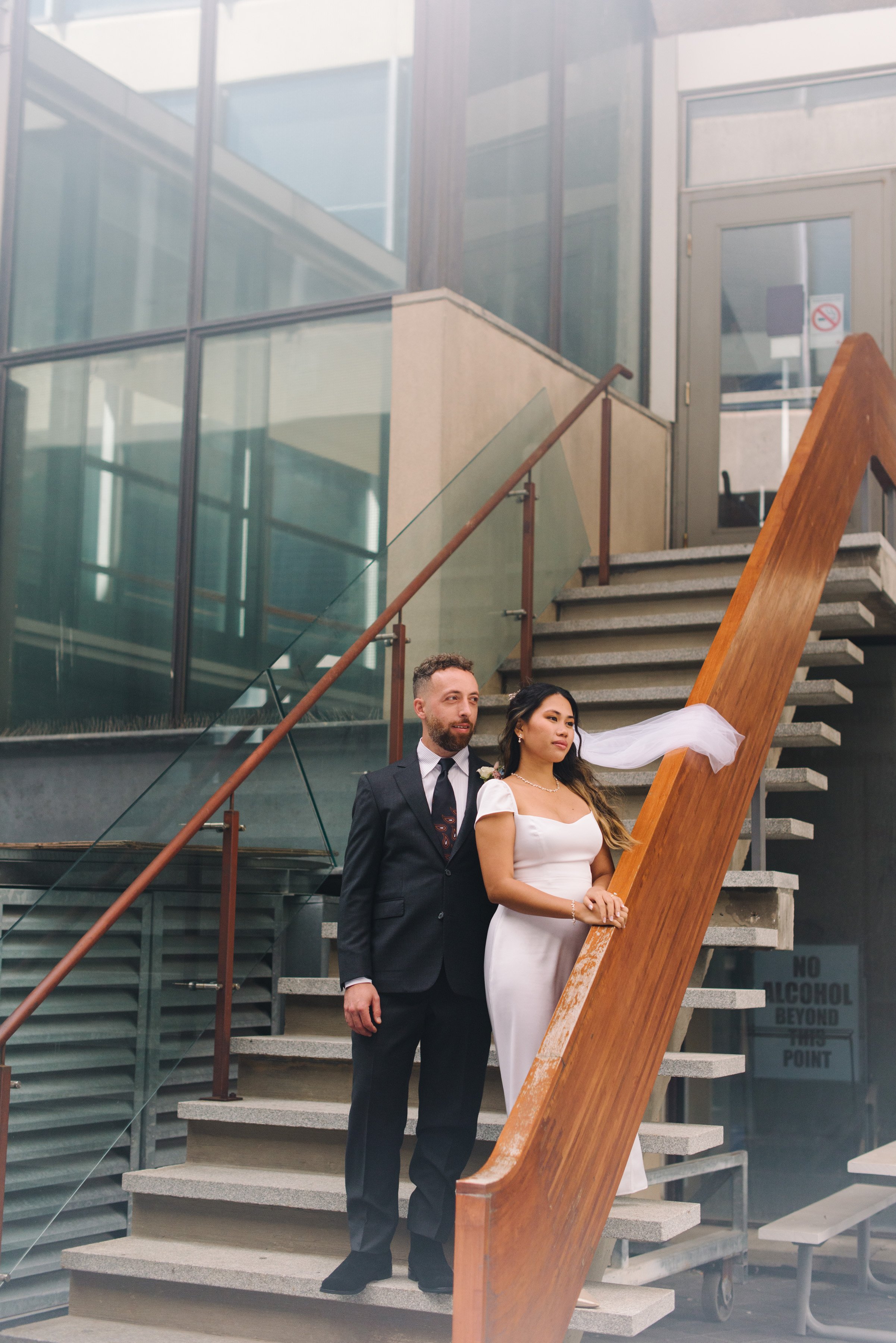 Film inspired portrait of a bride and groom on the terrace stairs at Toronto City Hall during their elopement