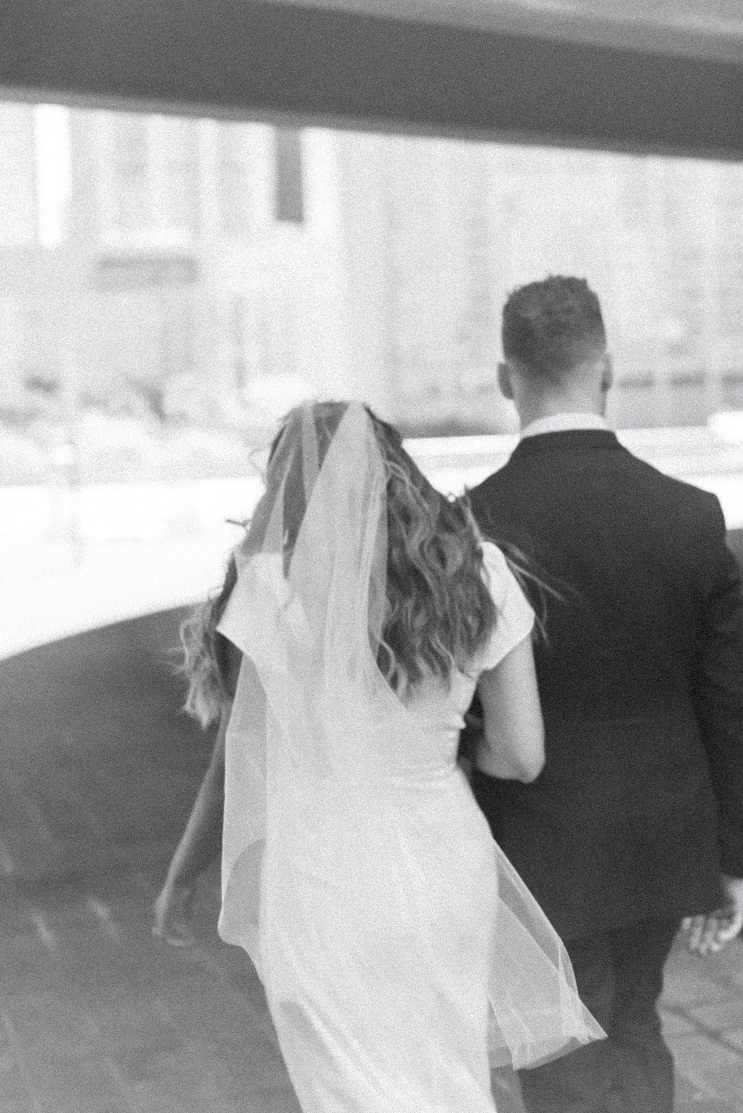 Black and white film inspired photo of a bride and groom walking together in downtown Toronto on their elopement day