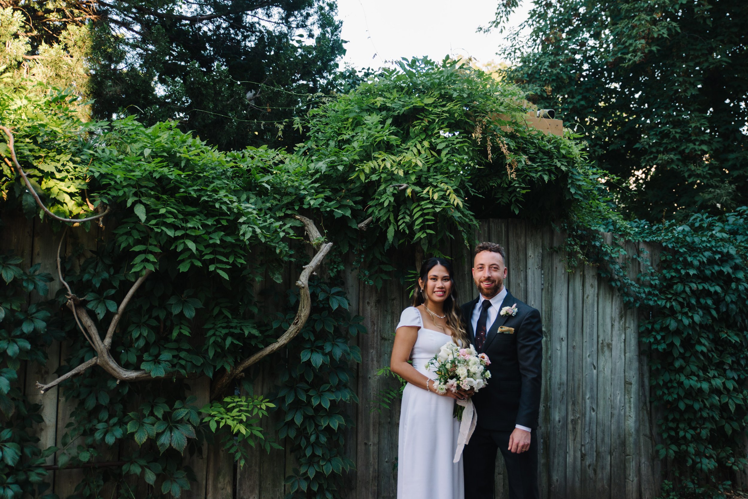 Classic portrait of a bride and groom against lush greenery in a downtown Toronto laneway