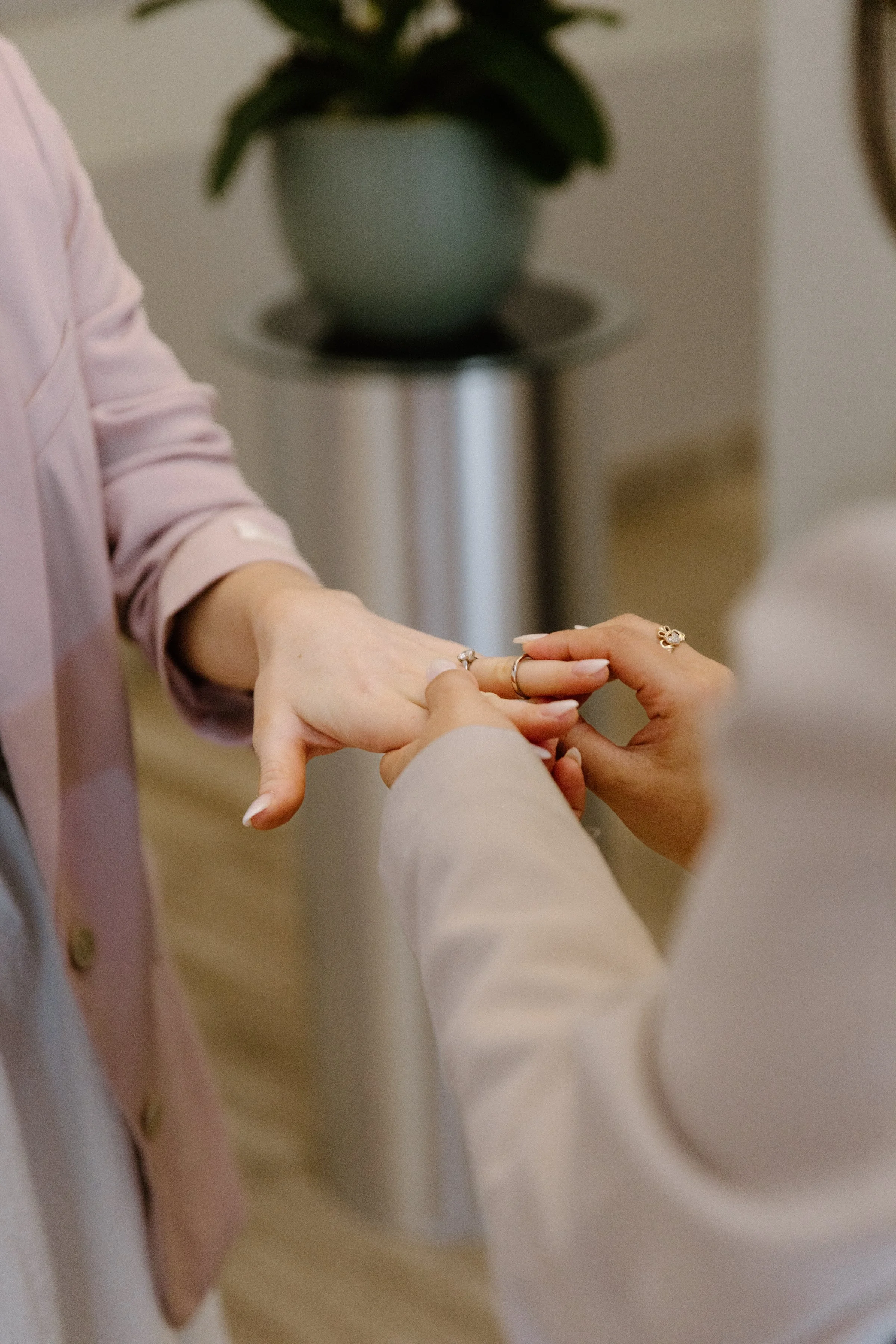 Bride placing a wedding ring on her wife's hand during their same-sex elopement ceremony at Toronto City Hall