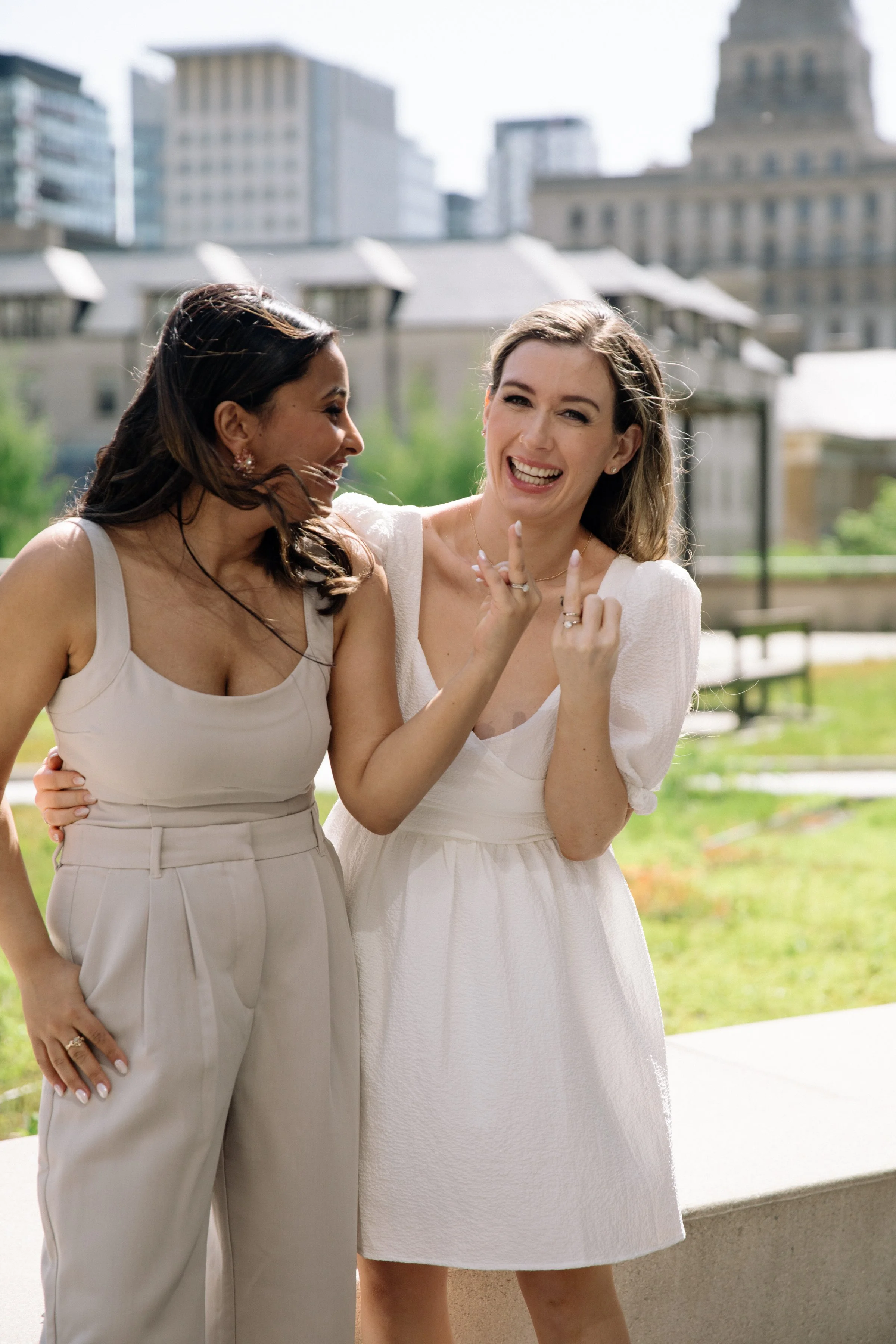 Two brides outside Toronto City Hall showing off their wedding rings after their chic same-sex elopement