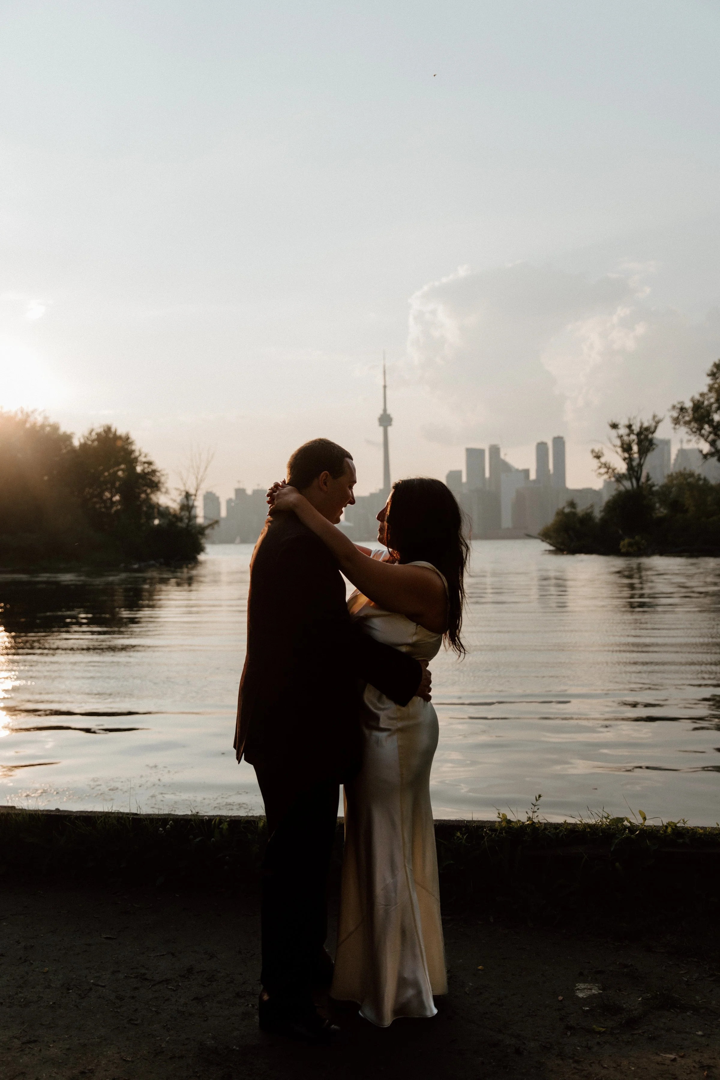Couple embracing in front of Lake Ontario at golden hour during a post-wedding portrait session on Toronto Island