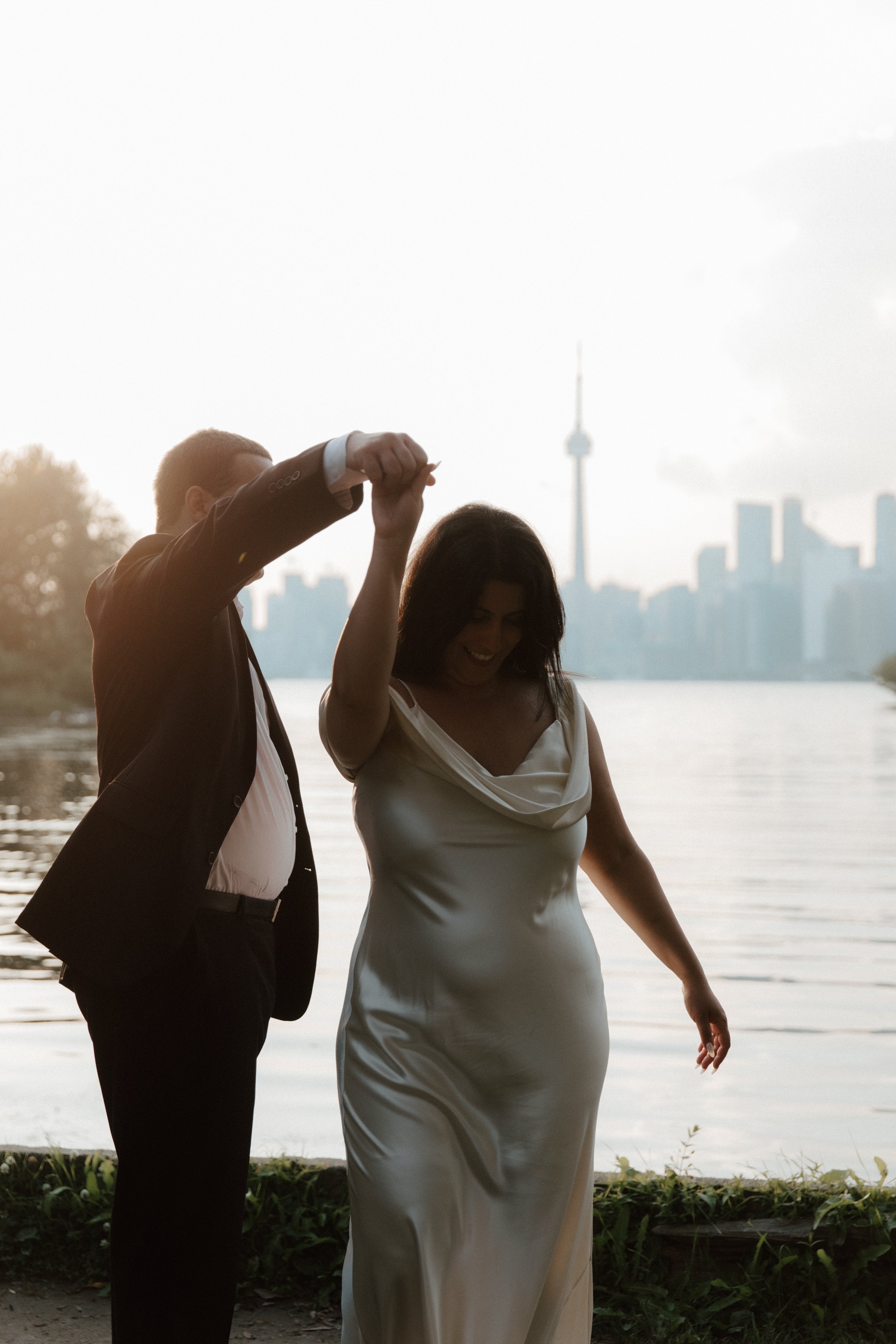 Couple dancing at the waterfront in front of the Toronto skyline at sunset during their elopement portrait session