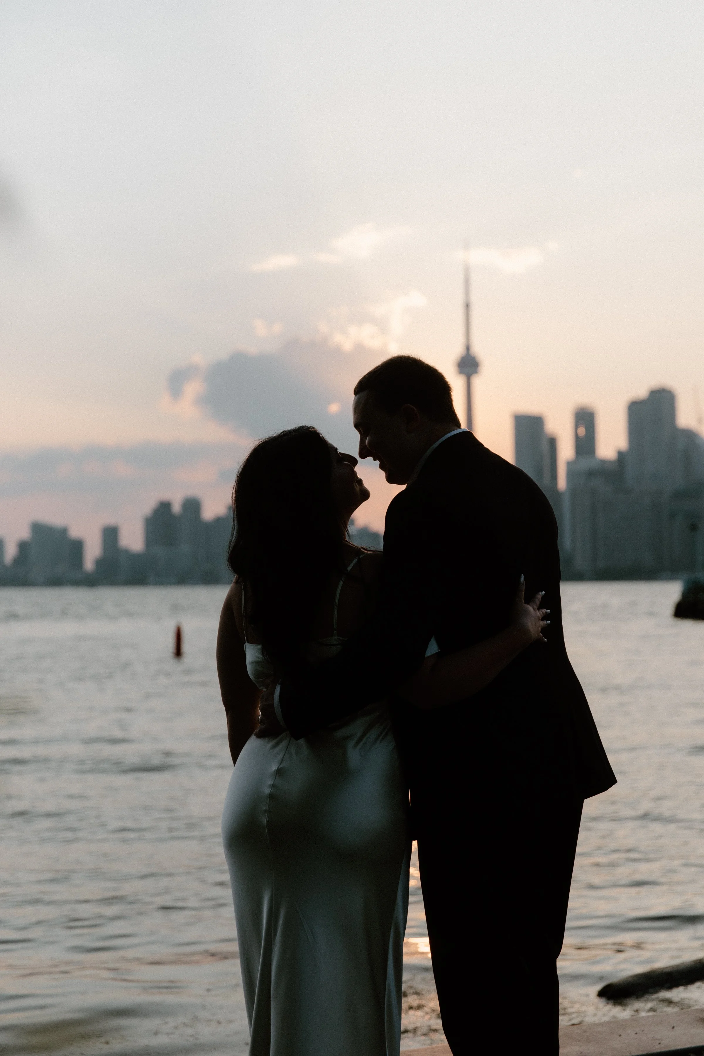 Modern elopement portrait of a couple about to kiss with the CN Tower visible in the background, Toronto