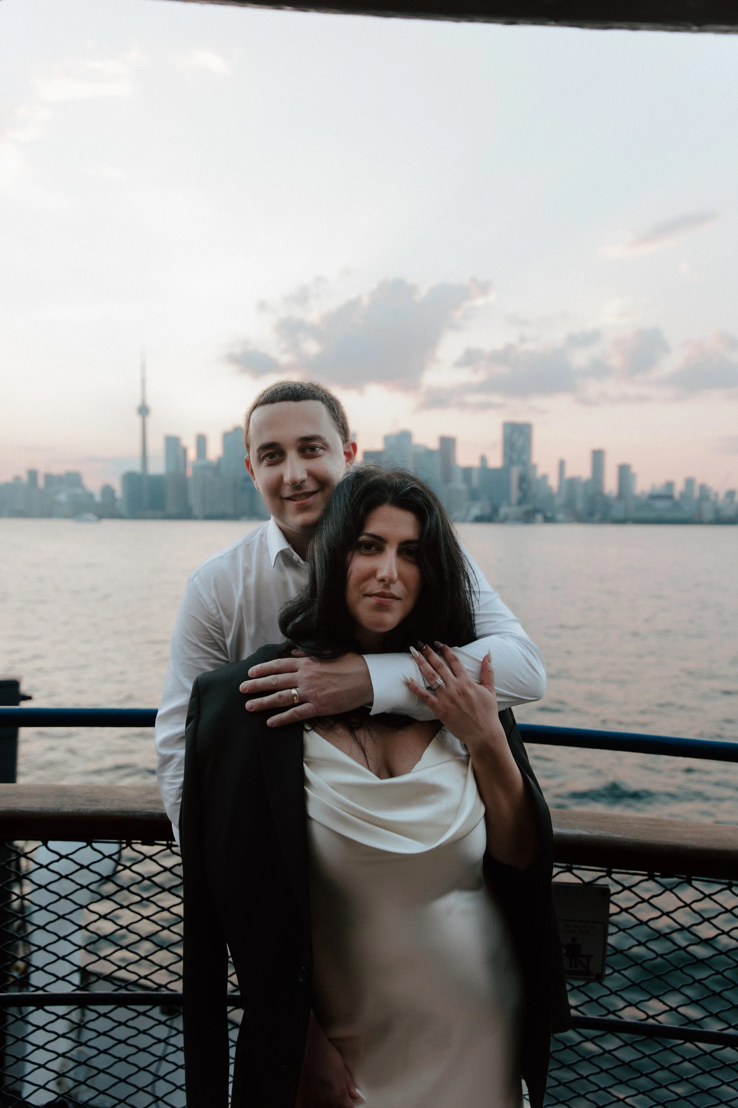 Chic post-wedding portrait of a couple on the Centre Island ferry with the Toronto skyline behind them over Lake Ontario