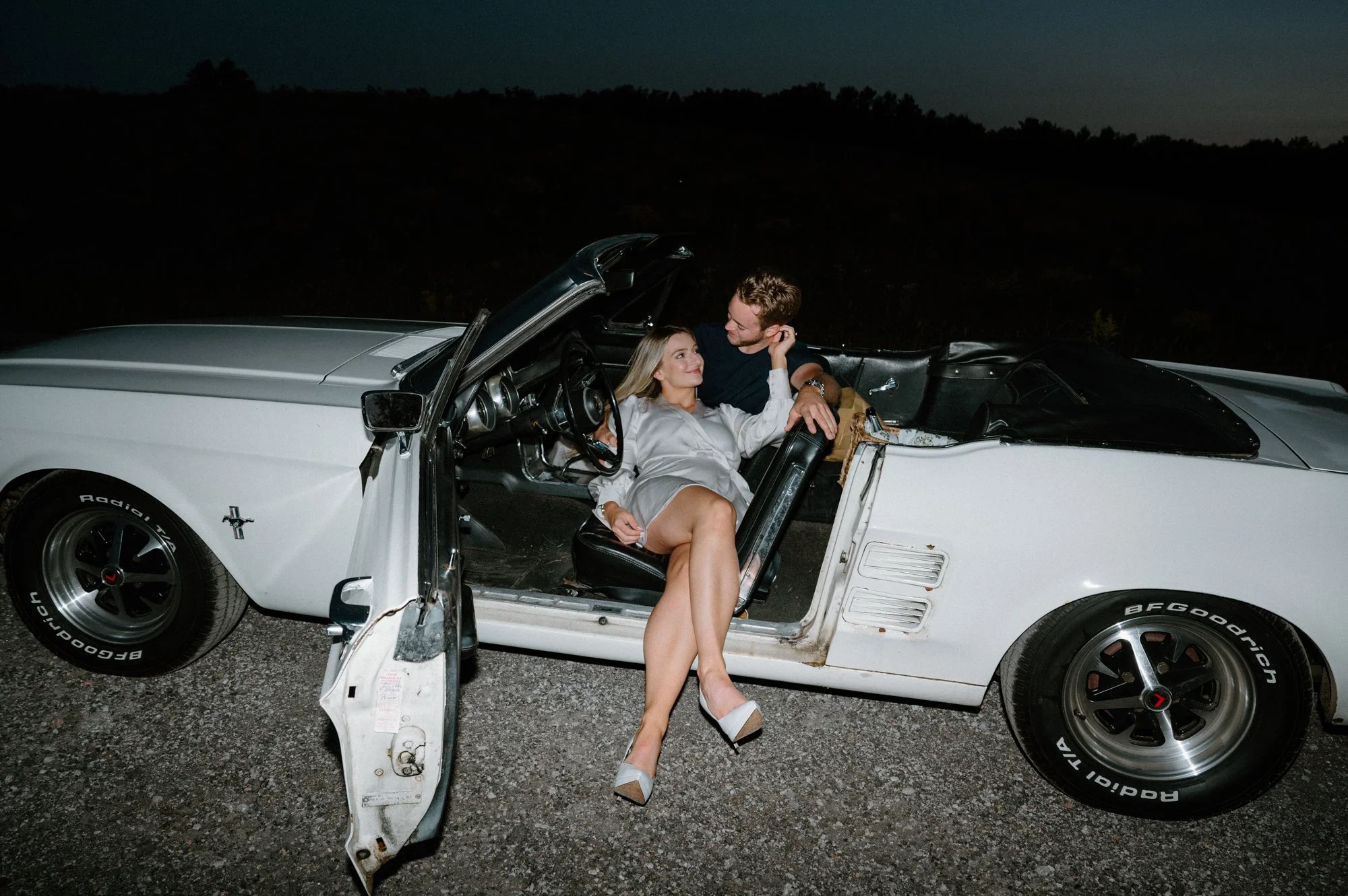 Bold editorial flash photography portrait of an engaged couple inside a vintage Mustang near Peterborough, Ontario