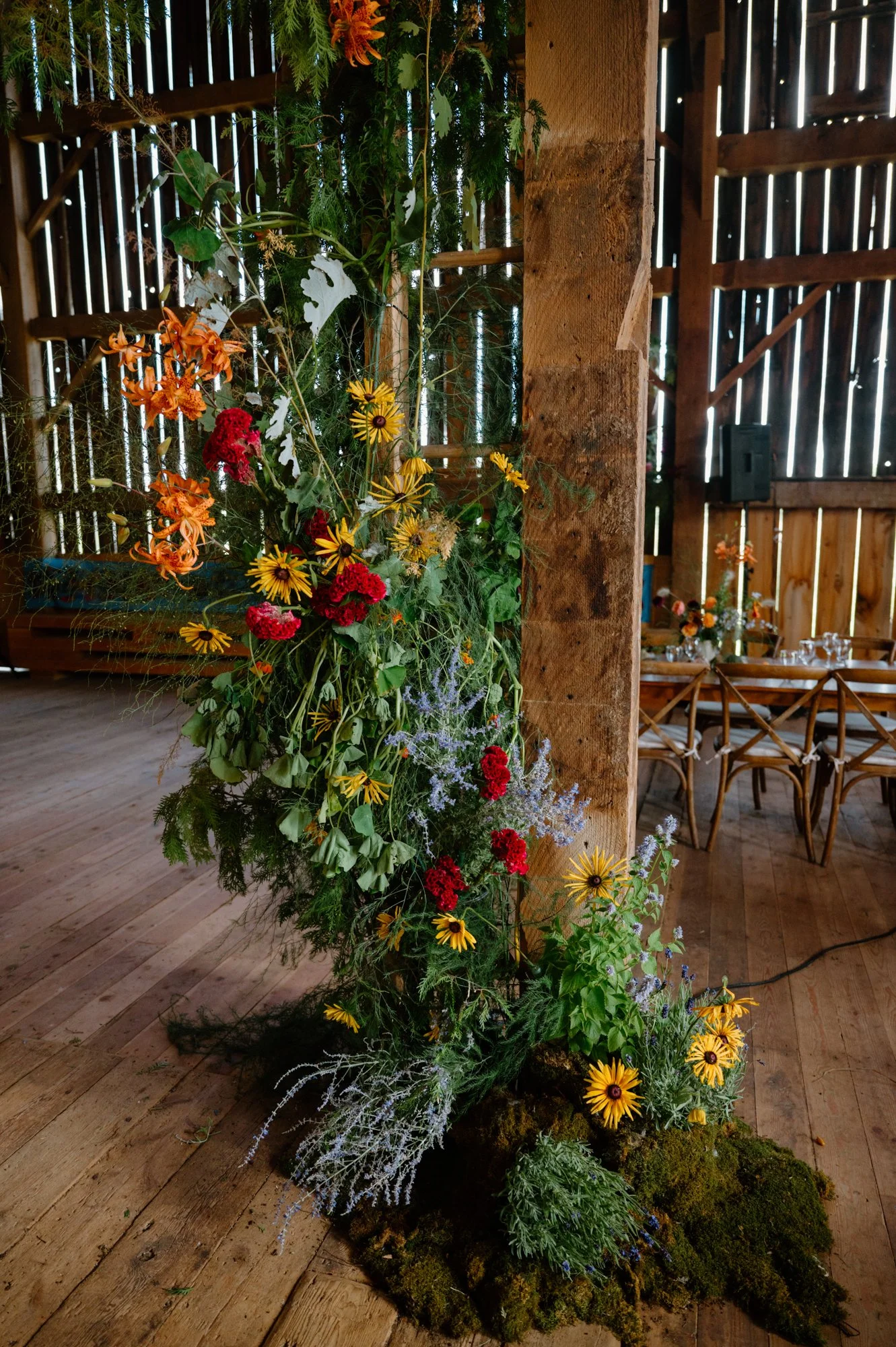Detail of an elaborate indoor flower installation inside a rustic barn at an Ontario farm wedding