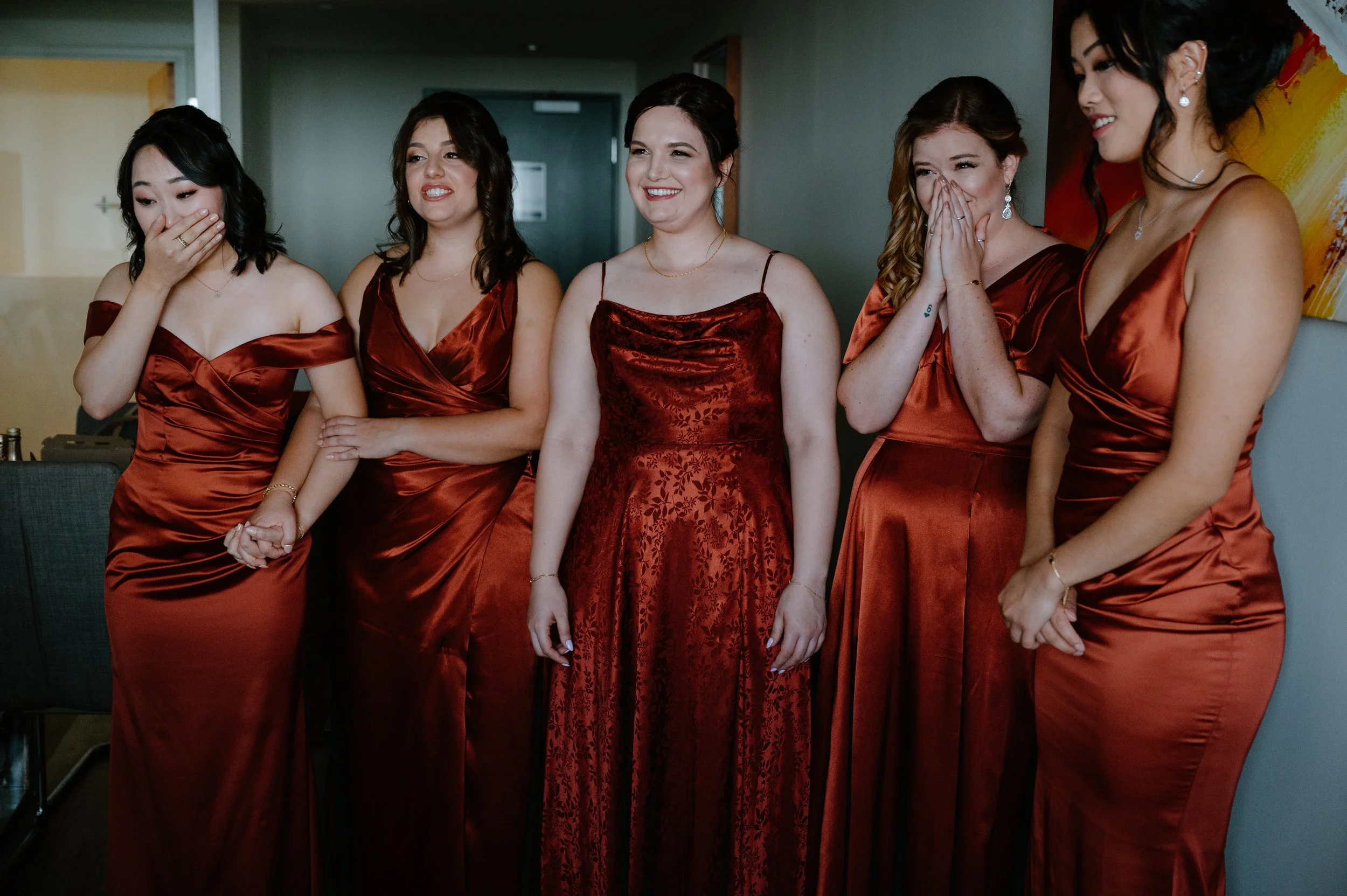 Candid and joyful photo of bridesmaids seeing the bride in her wedding dress for the first time during a Toronto wedding