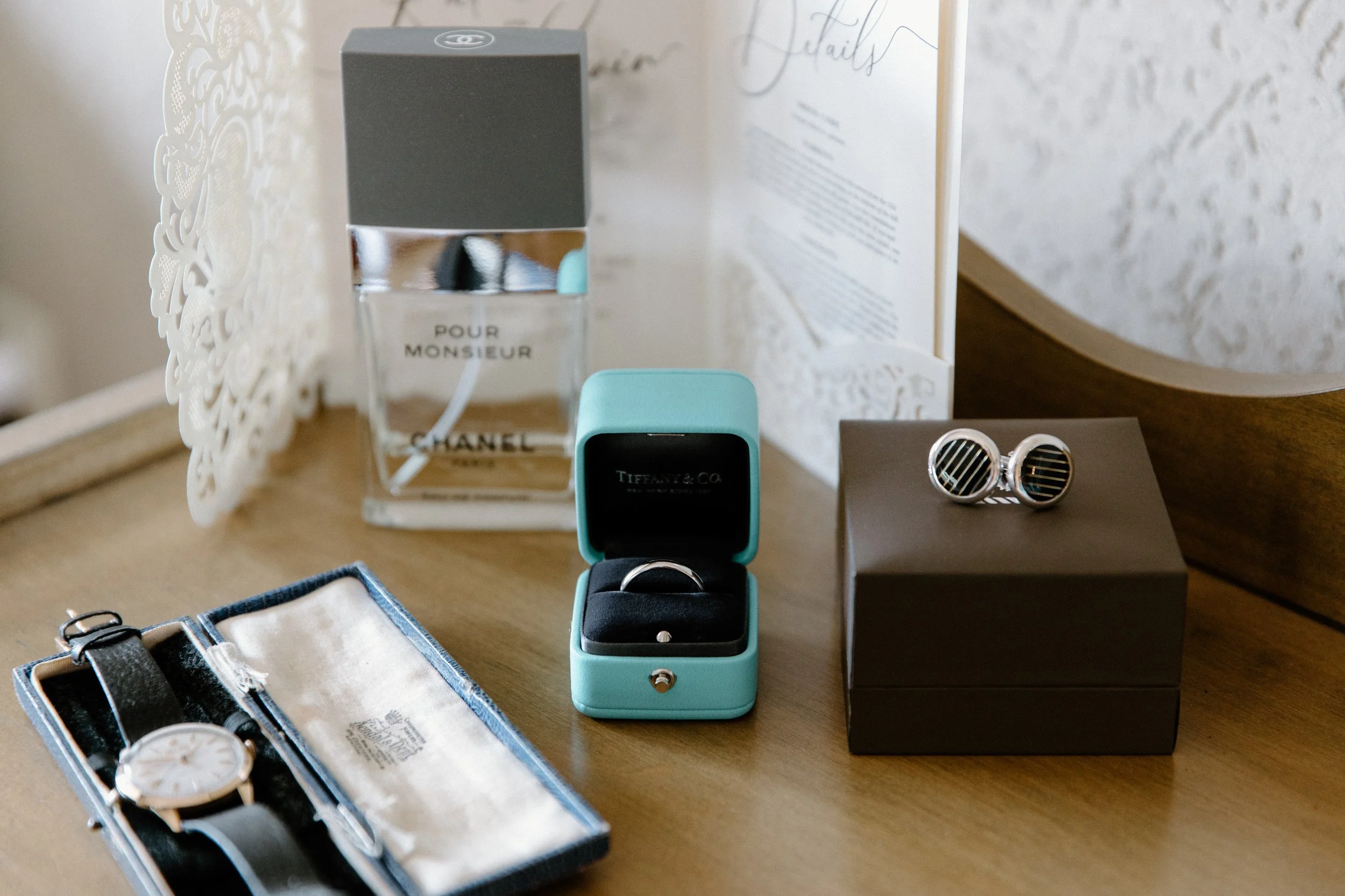 Editorial still life of groom's details including rings, watch, cufflinks, and cologne on a Toronto wedding day