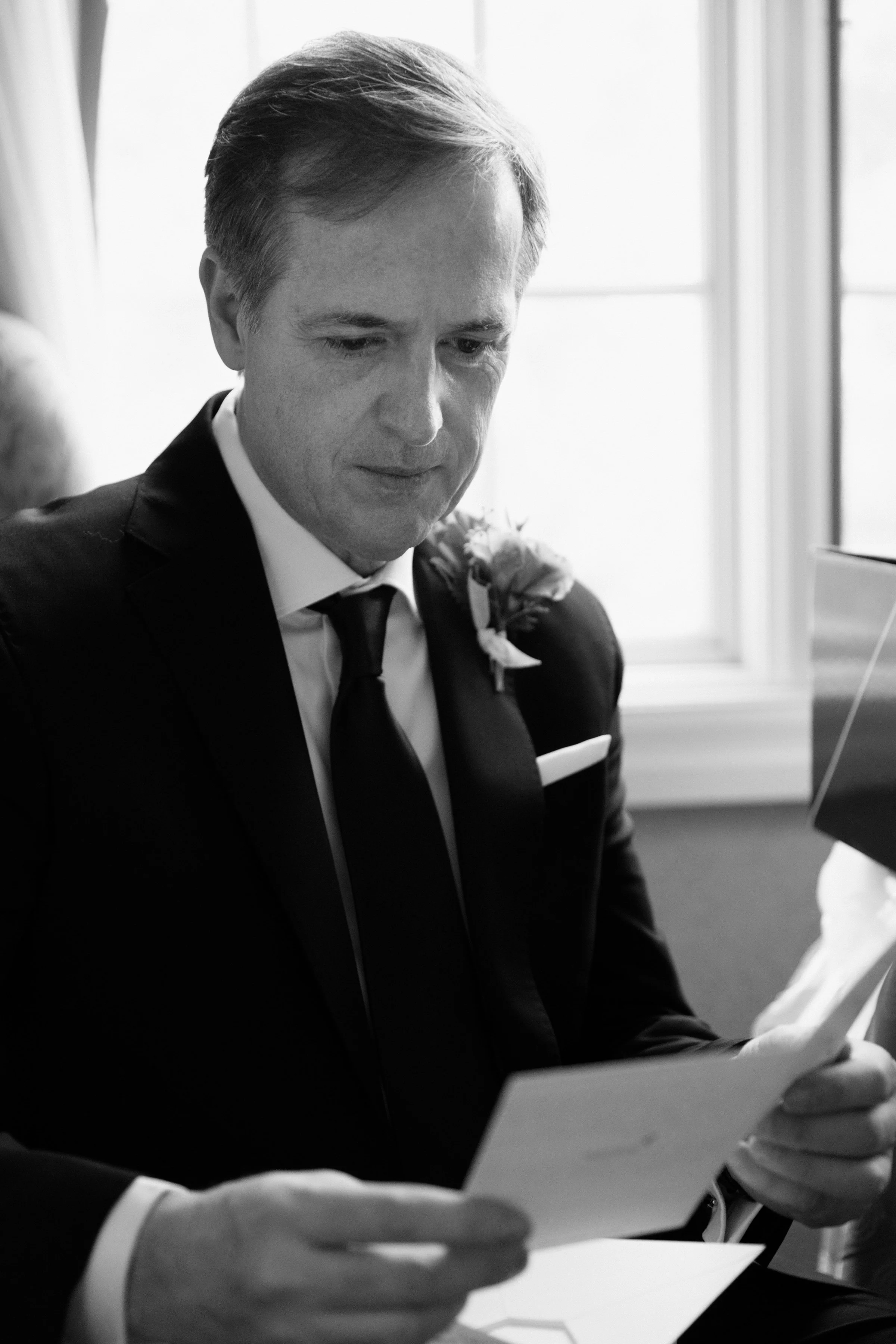 Black and white candid of a groom reading an emotional card from his bride on their Toronto wedding day