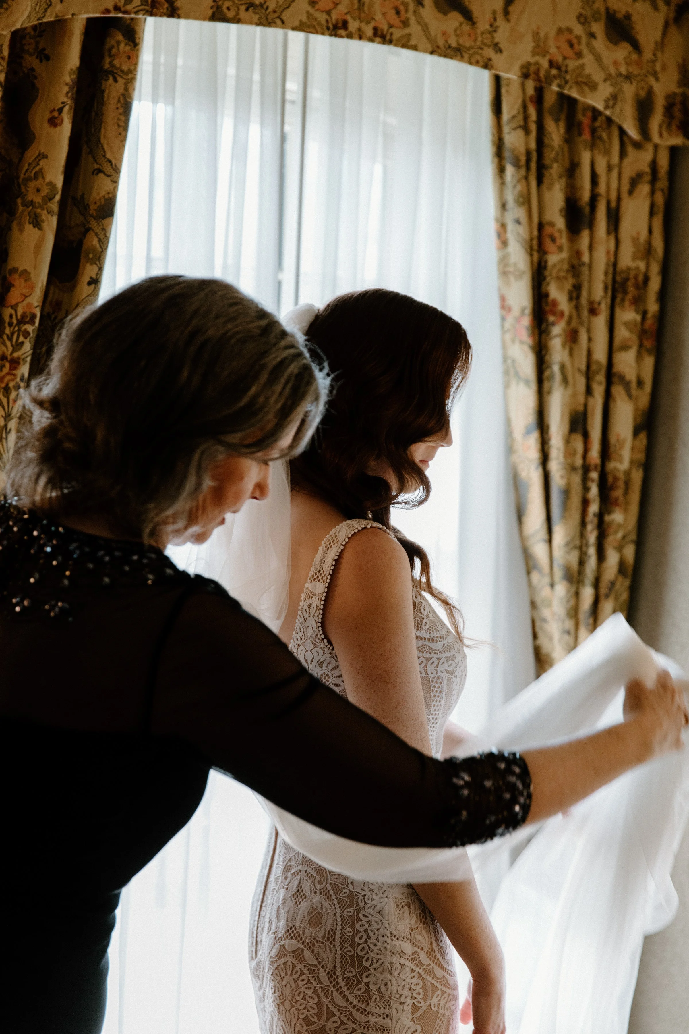 Candid photo of a mother helping her daughter into her wedding gown on her Toronto wedding day