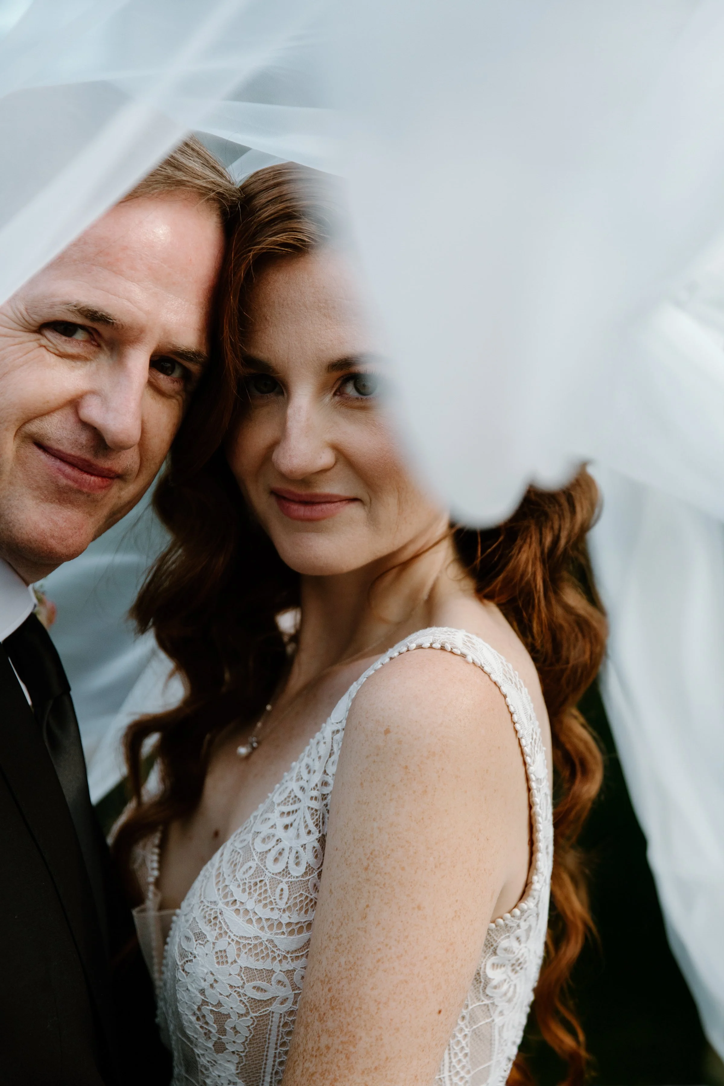 Editorial inspired portrait of a bride and groom together under the bridal veil at their Toronto wedding