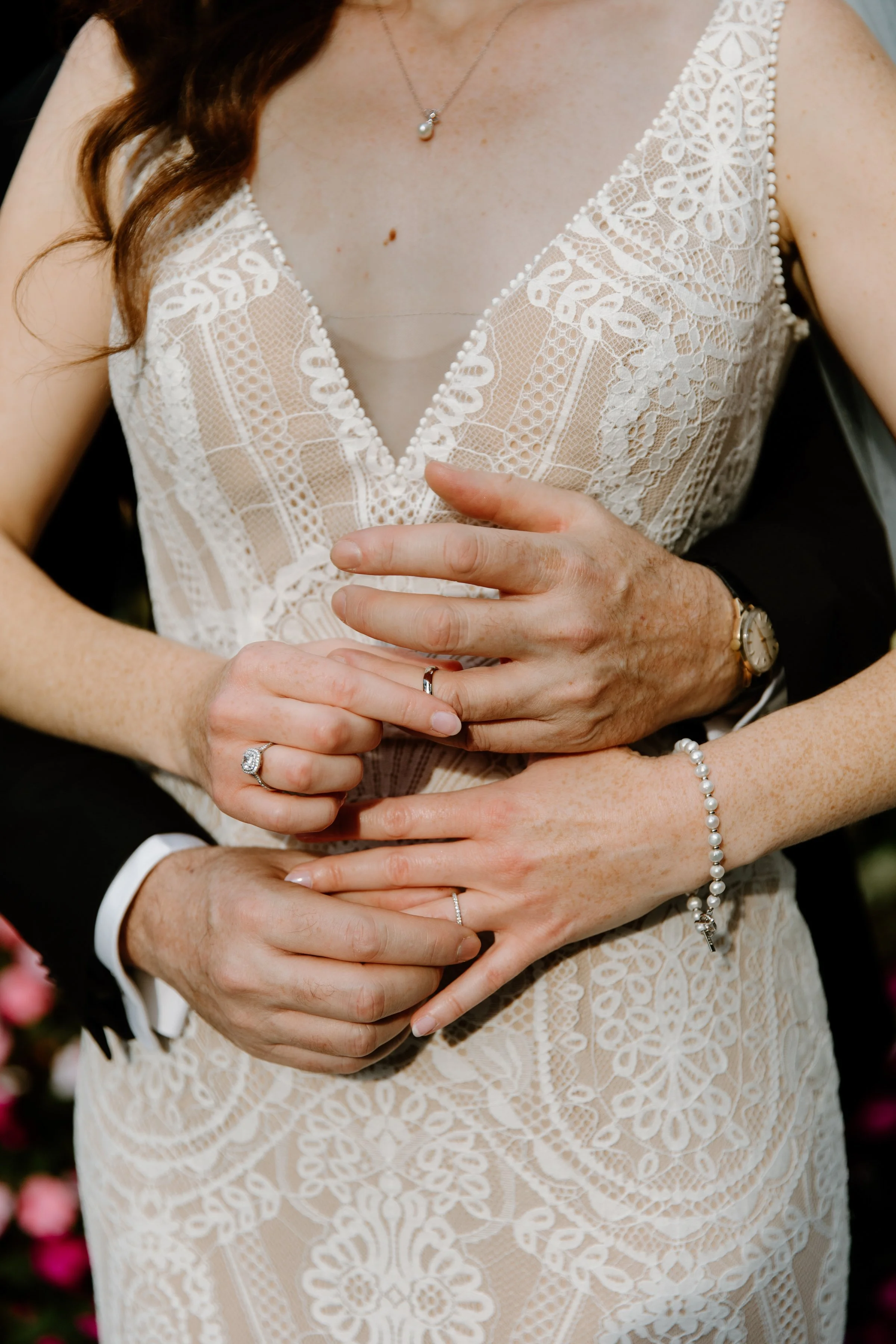 Editorial close up portrait of a bride and groom exchanging wedding rings, he holds her band on her finger as she holds his, styled like a pinterest wedding photo