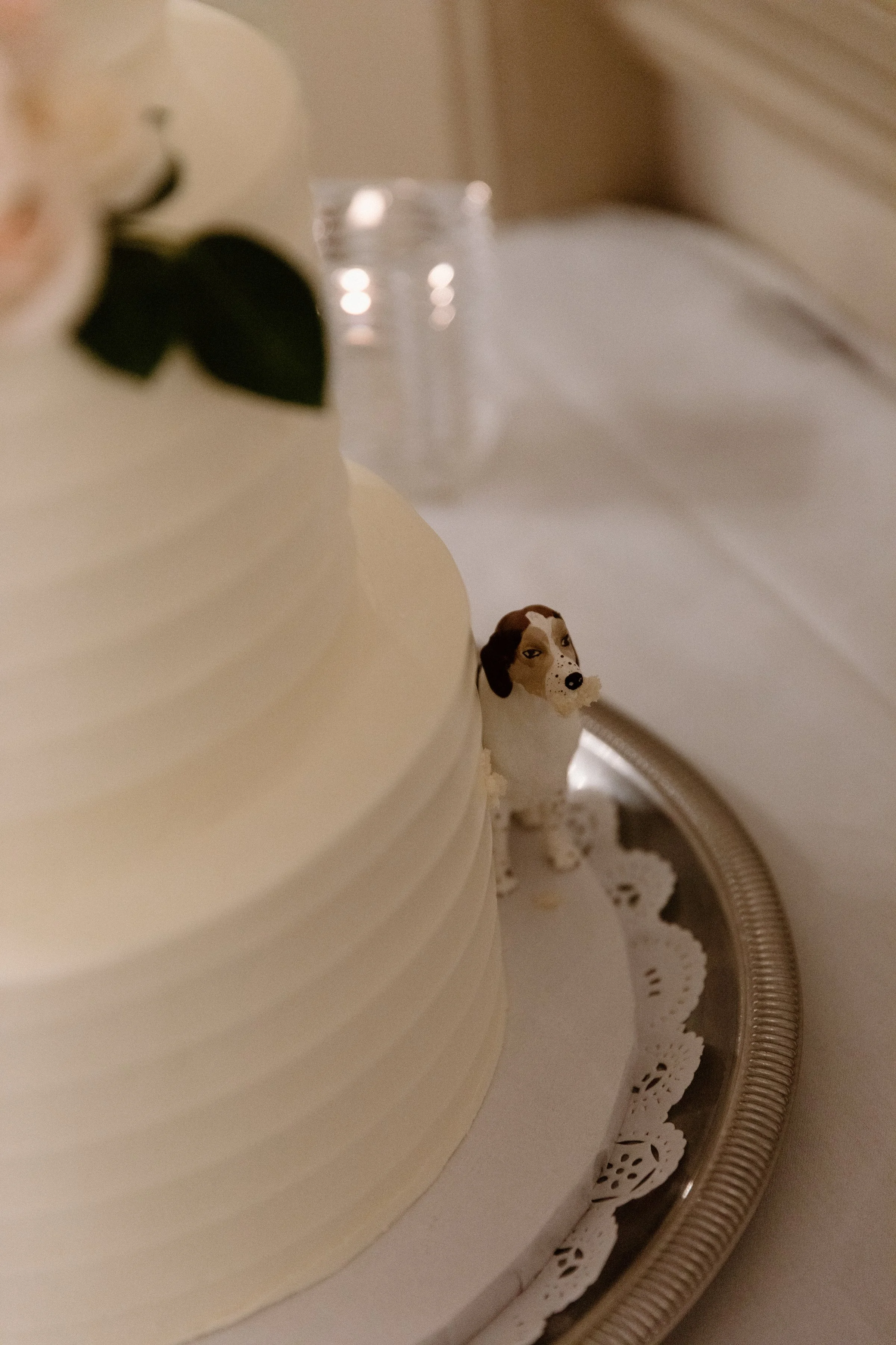Detail photo of a little dog figurine hiding behind the wedding cake at a Toronto wedding reception