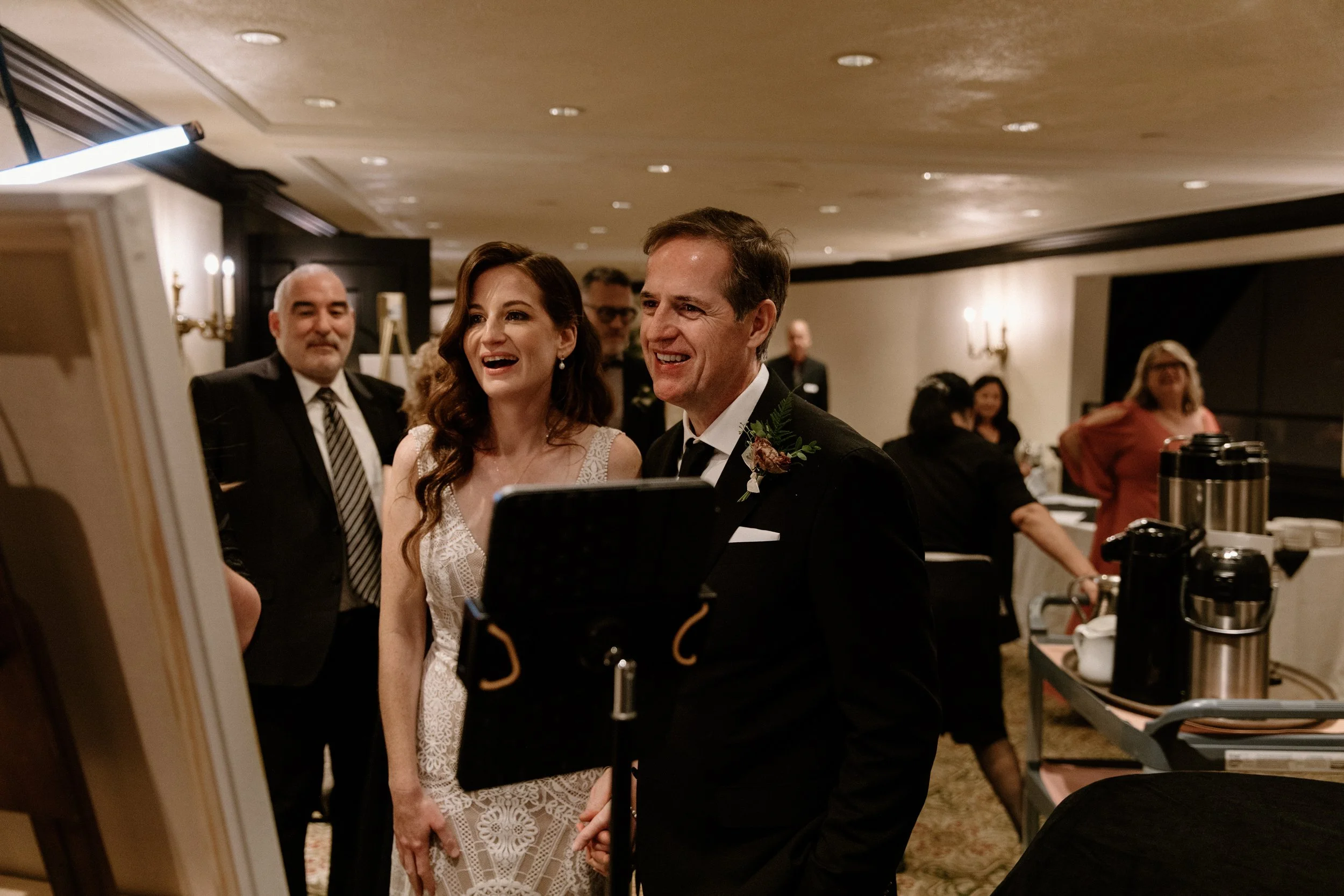 Candid photo of a bride and groom excitedly seeing their live wedding painting for the first time at their Toronto reception