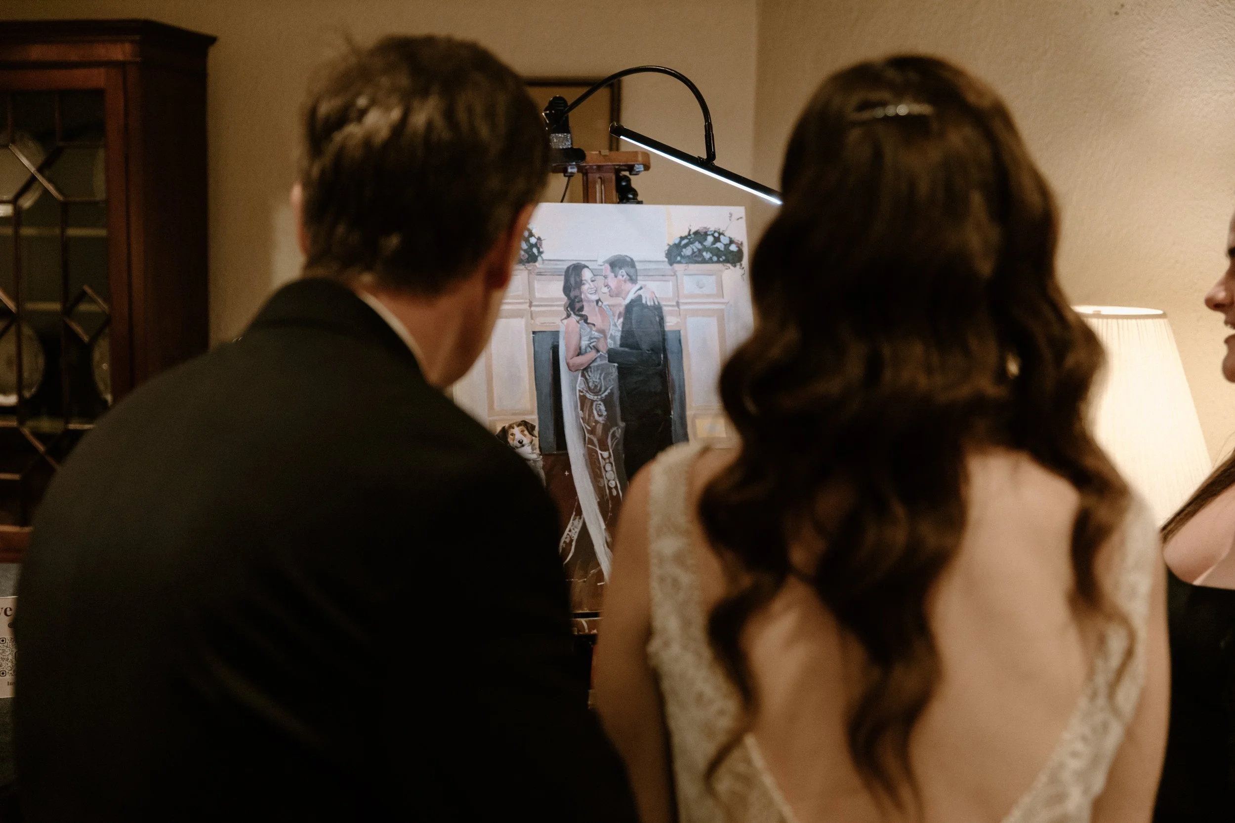 Photo from behind of a bride and groom looking at their live wedding painting together at their Toronto reception