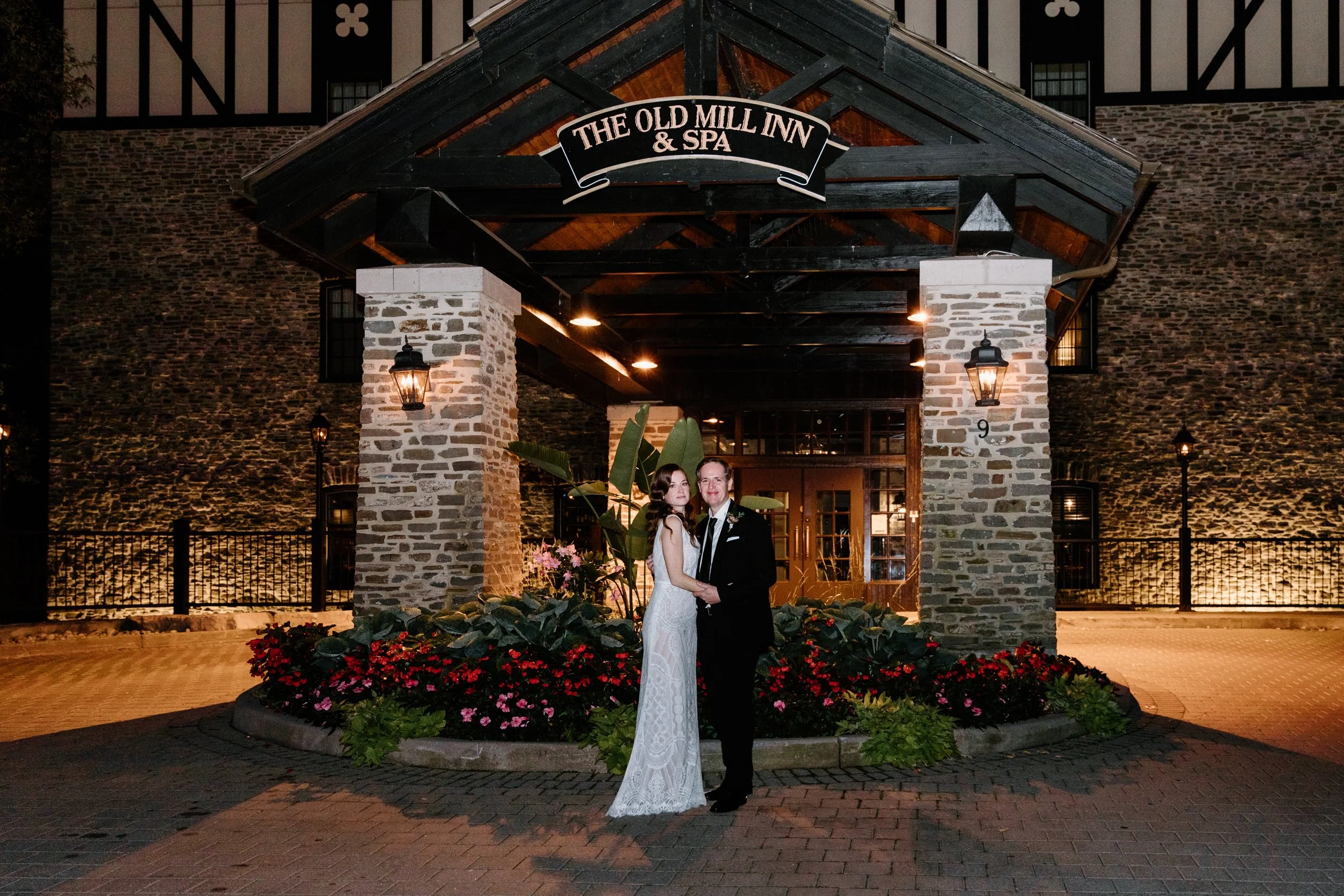Editorial flash photography portrait of a bride and groom standing outside their Toronto wedding venue at night