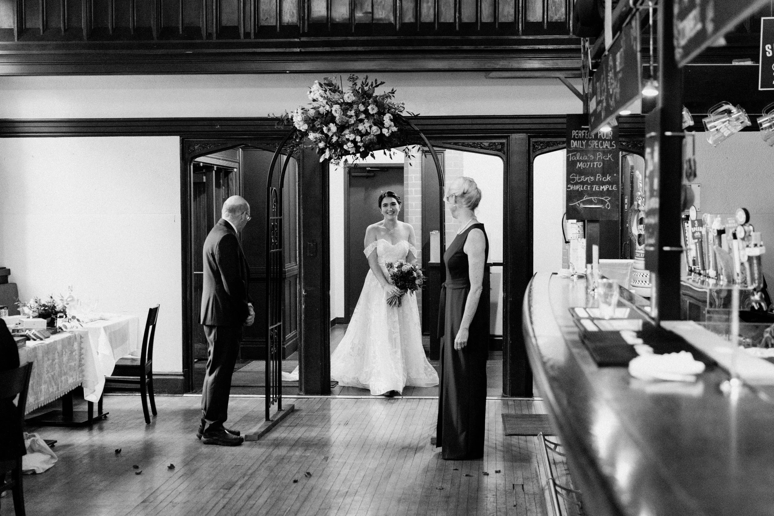 Black and white photo of bride walking to her wedding ceremony with her parents at McMaster University, Hamilton