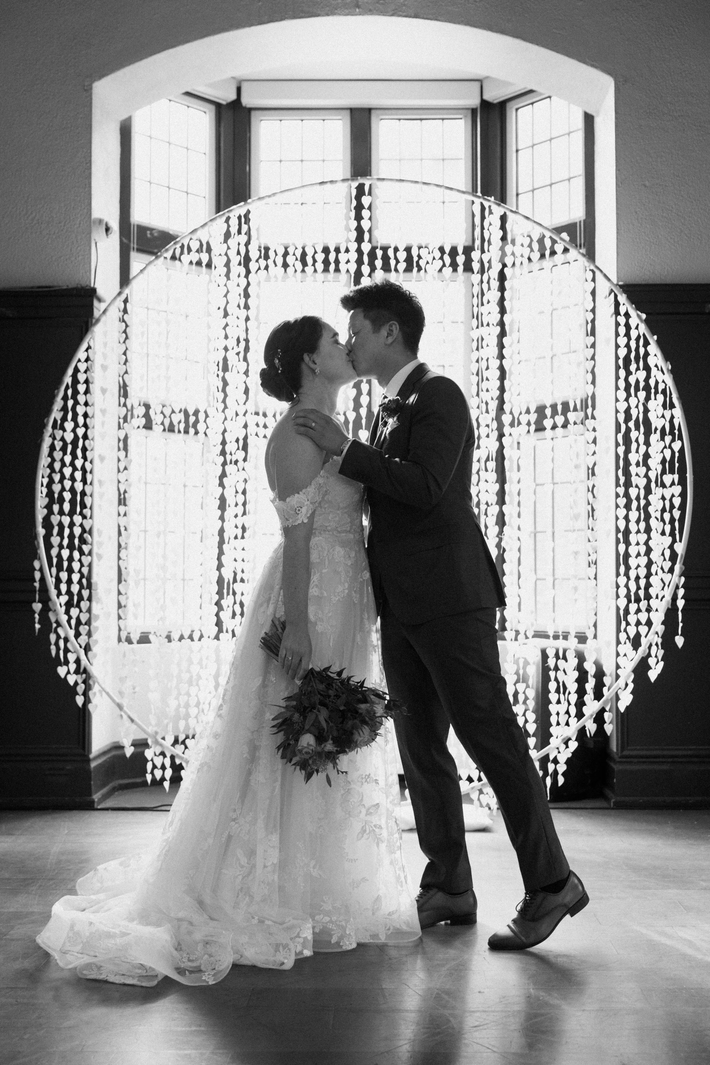 Black and white photo of bride and groom sharing their first kiss at their McMaster University wedding in Hamilton