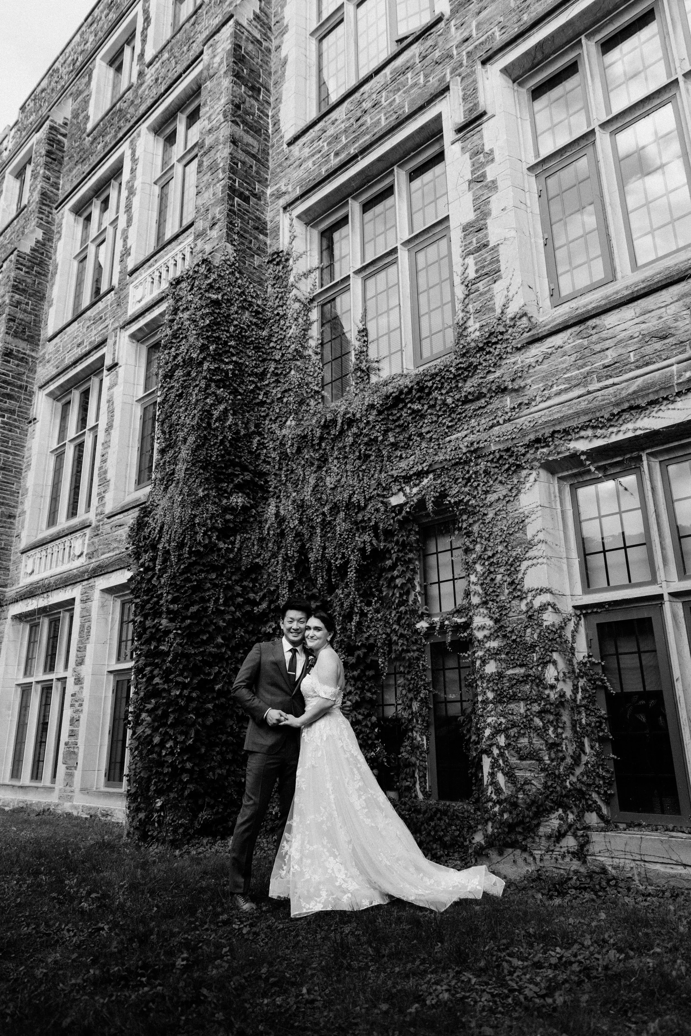 Black and white portrait of bride and groom in front of an ivy wall outside the Phoenix Crafthouse, Hamilton