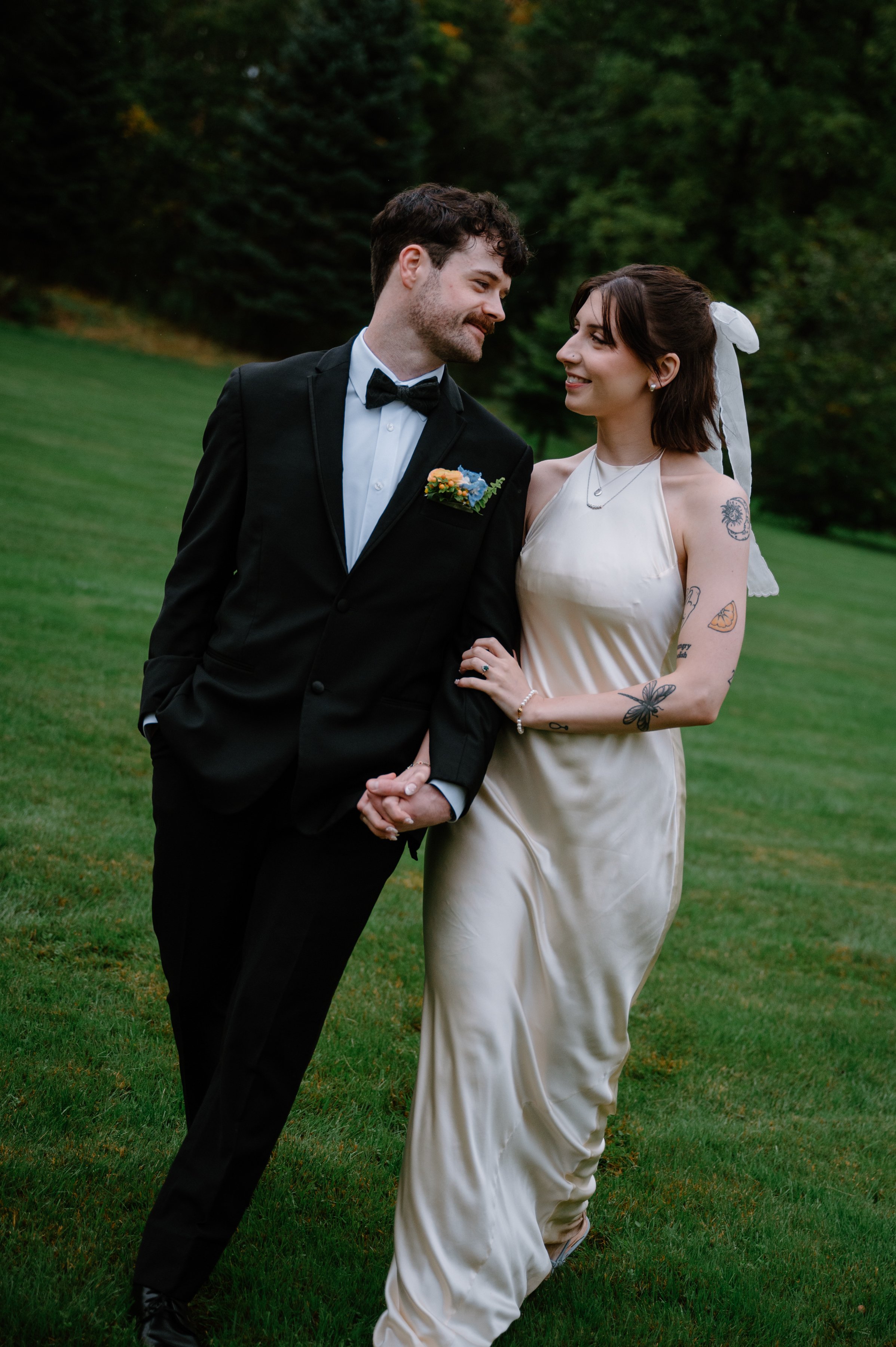 Bride and groom walking through a field and looking at each other at Langdon Hall, Ontario