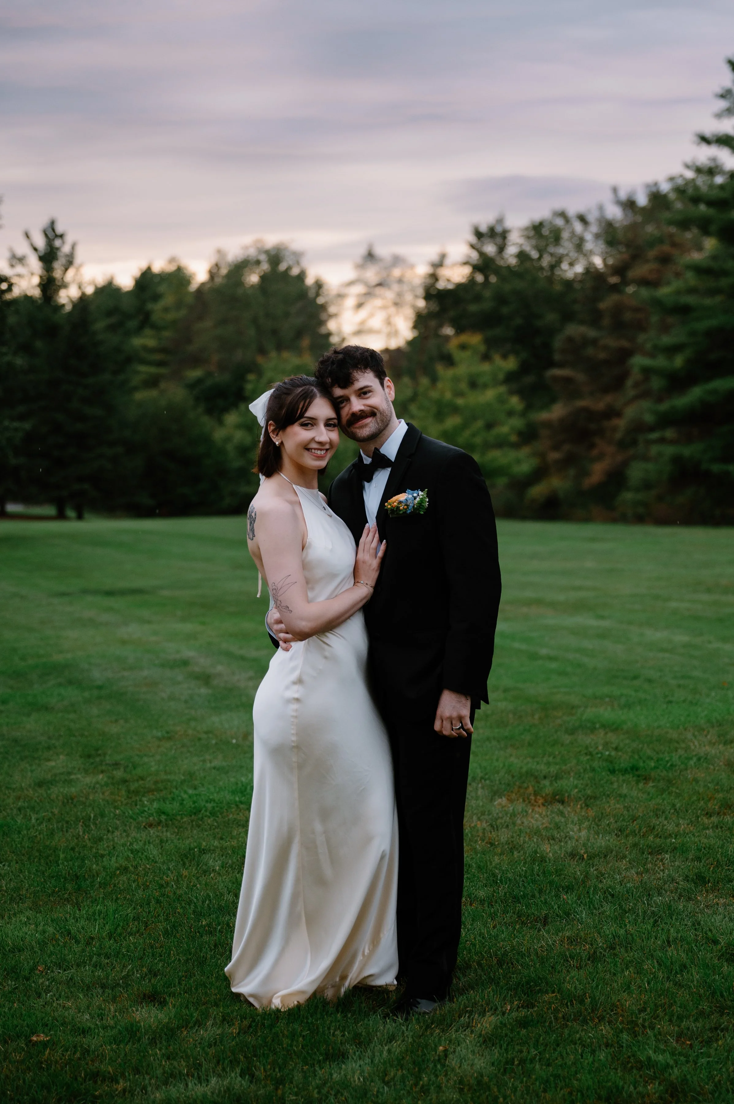 Bride and groom standing together in a field at golden hour during their Langdon Hall wedding reception
