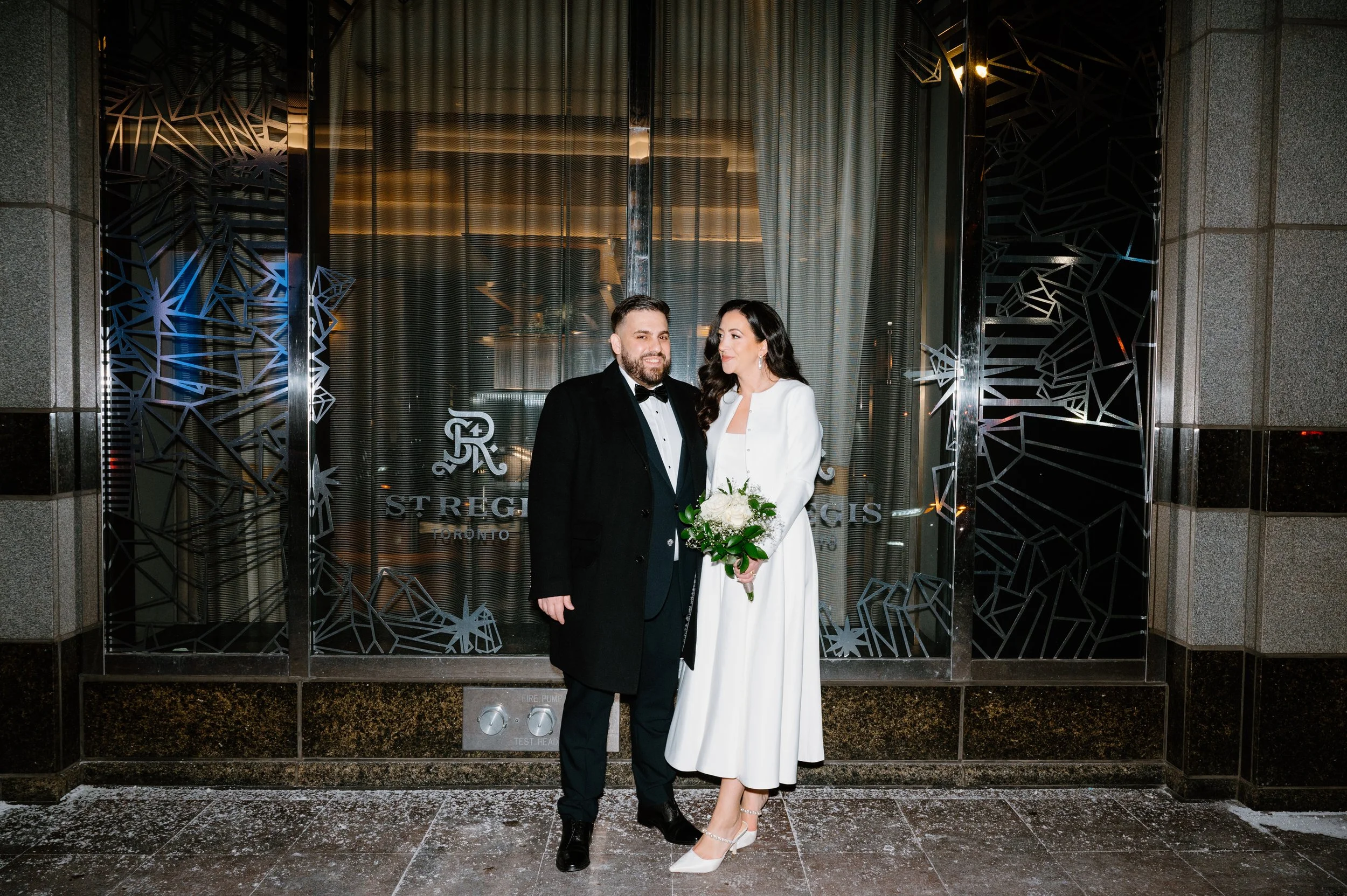 Couple photographed outside their hotel after a winter elopement in Toronto