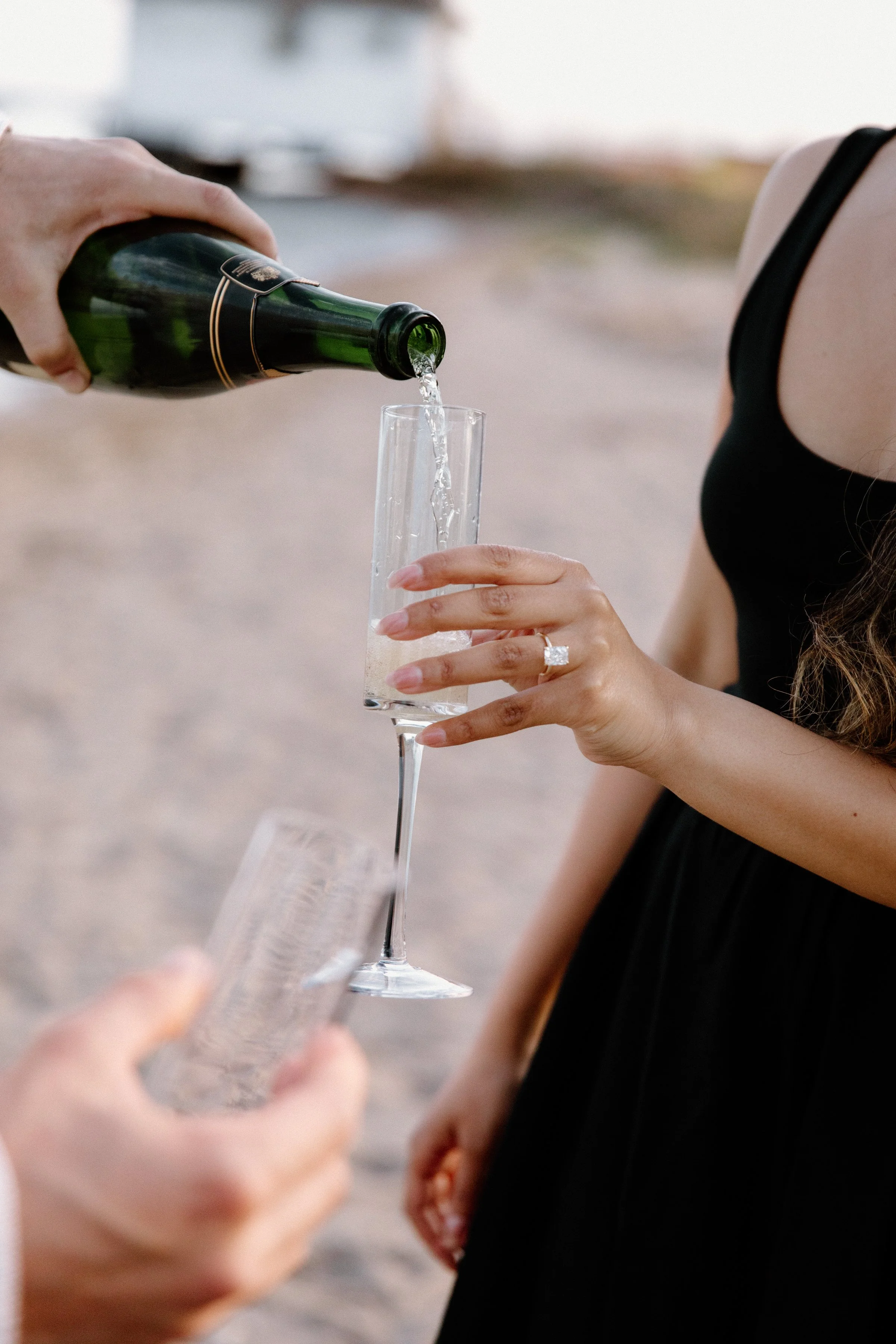 Couple celebrating with champagne during a beach engagement session in Toronto