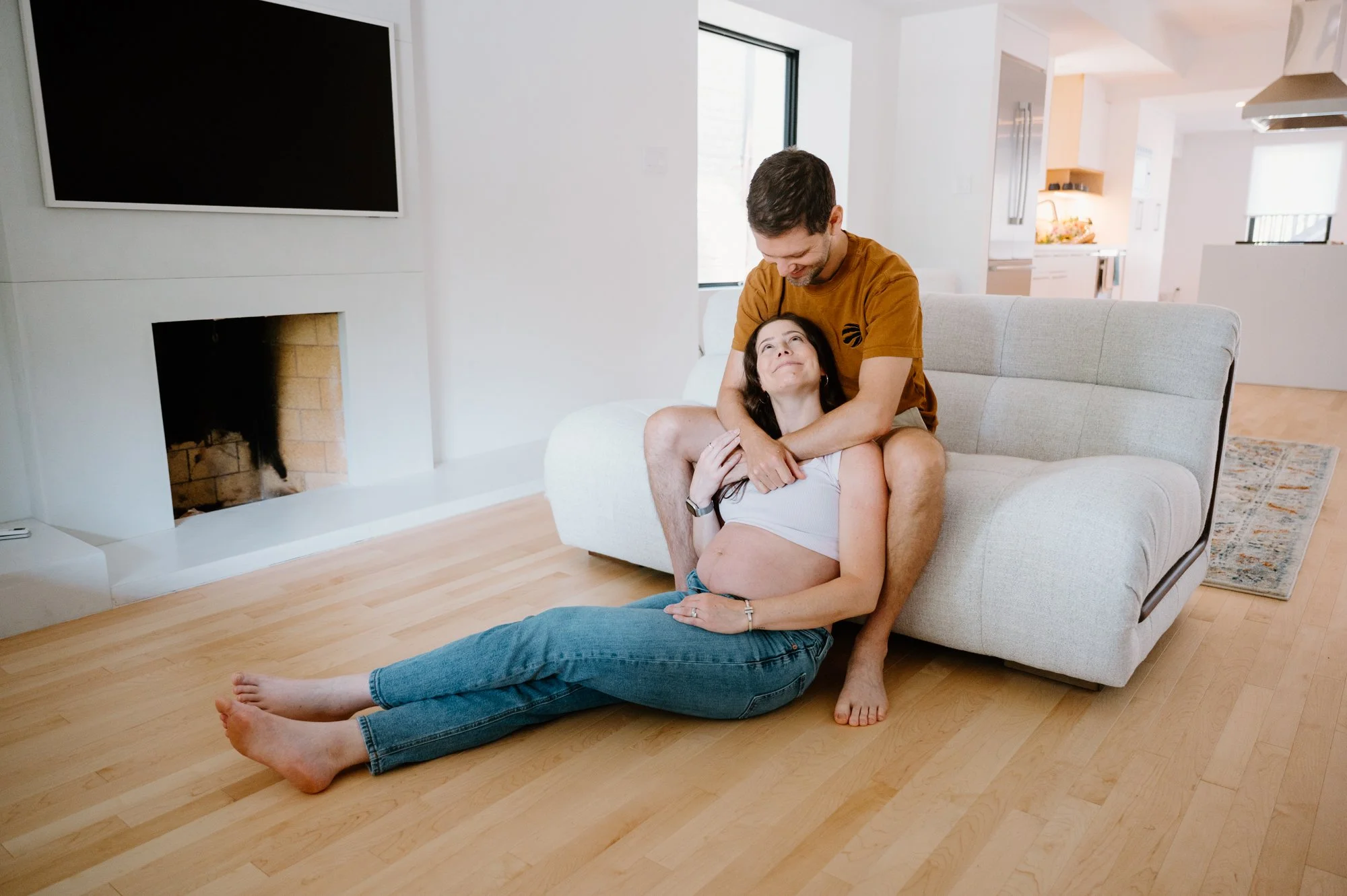 Documentary style wide photo of a couple in their living room during an at-home maternity session in Toronto