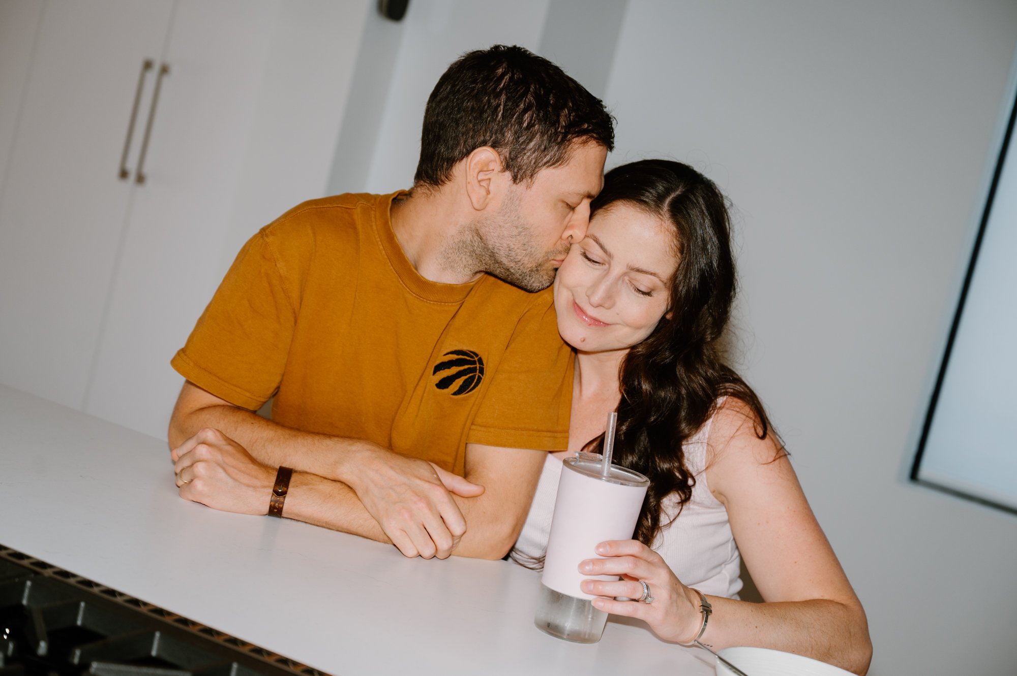 Candid photo of a couple sitting at their kitchen table like any other morning during an at-home maternity session in Toronto