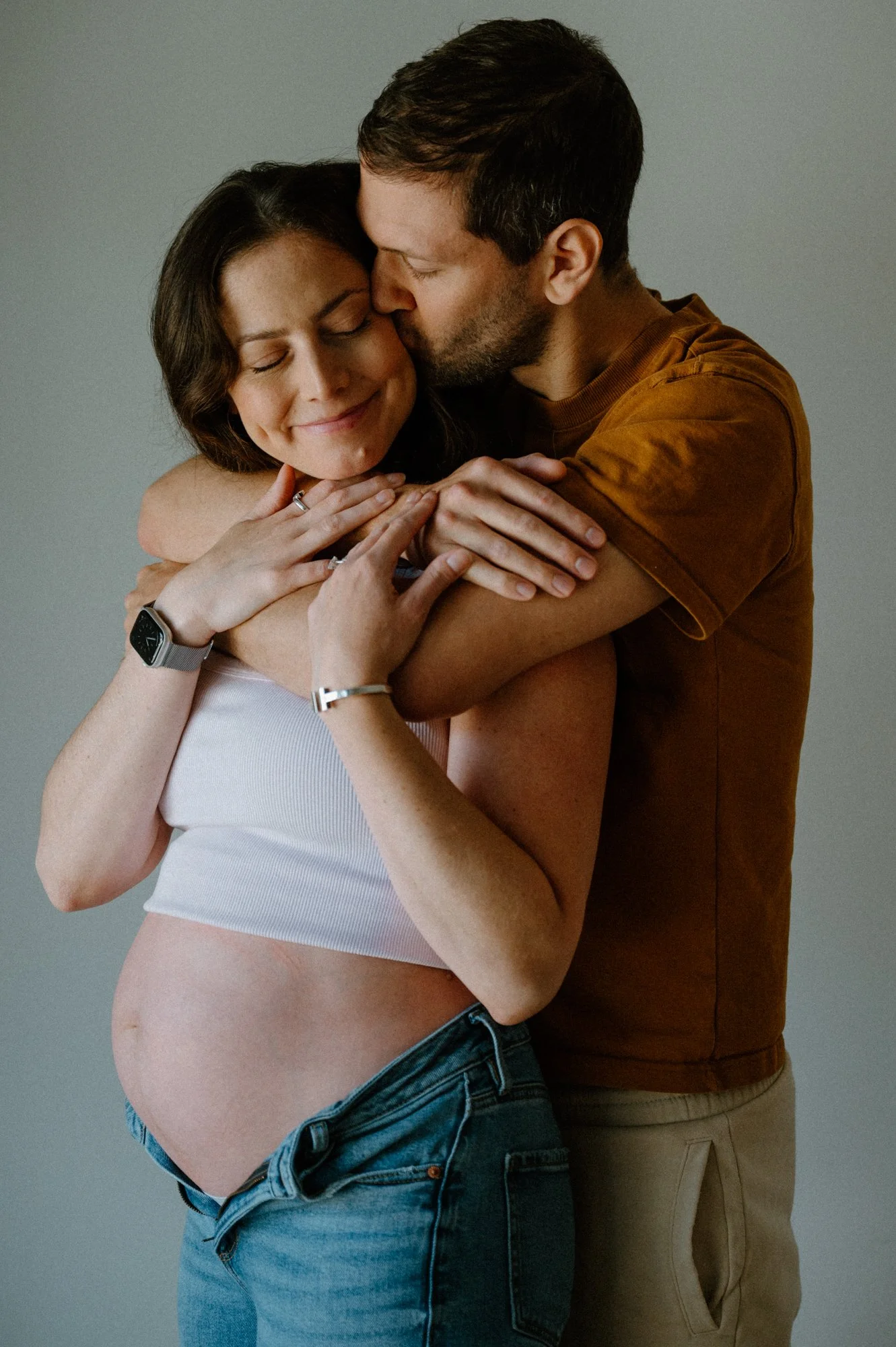 Emotional photo of a couple standing and hugging during their at-home maternity session in Toronto