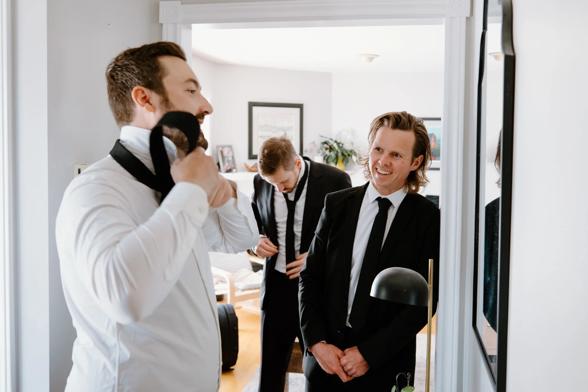 Candid photo of groomsmen getting ready together before a destination wedding in Newfoundland