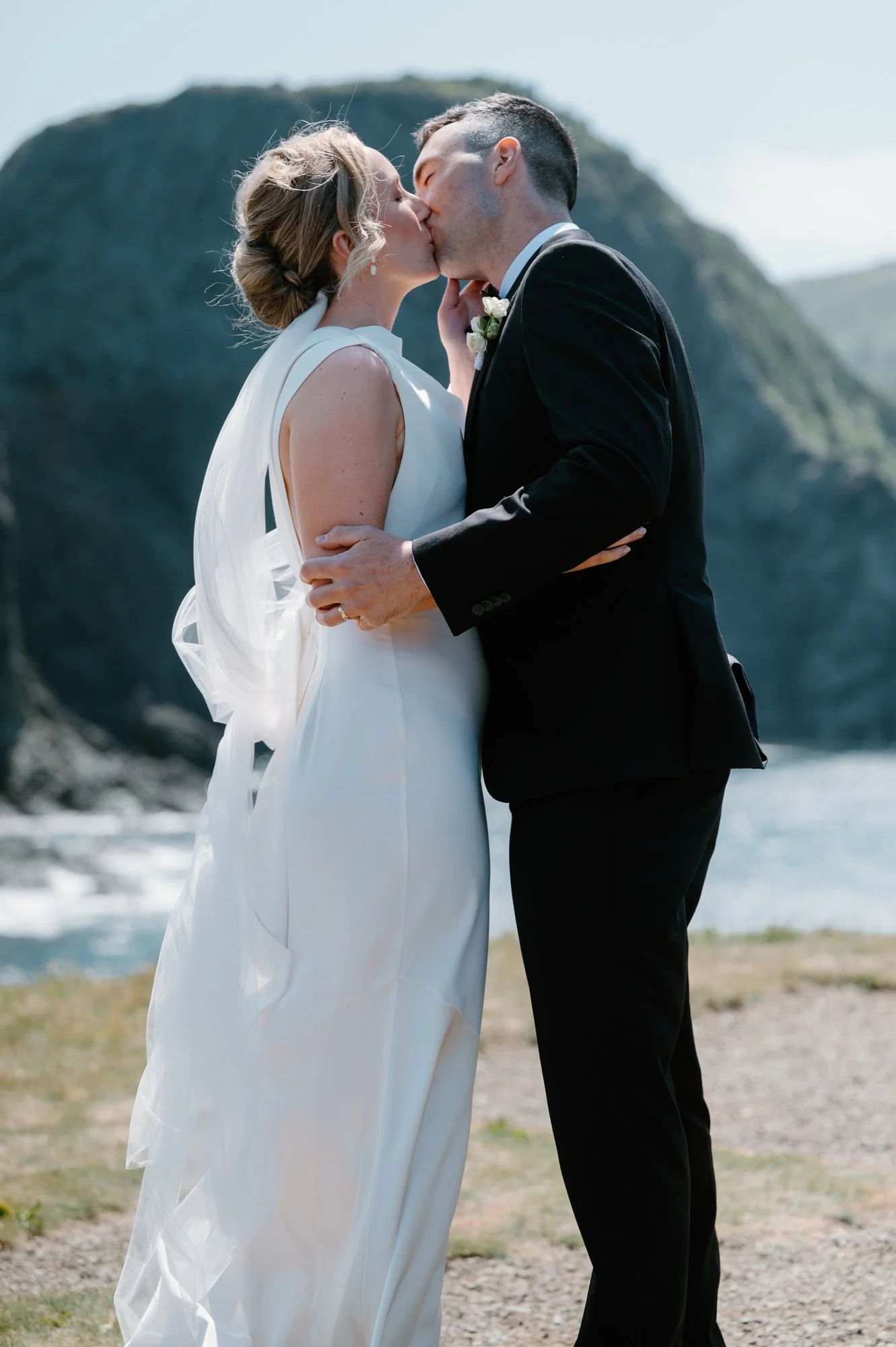 Bride and groom sharing their first kiss during an outdoor cliffside destination wedding ceremony