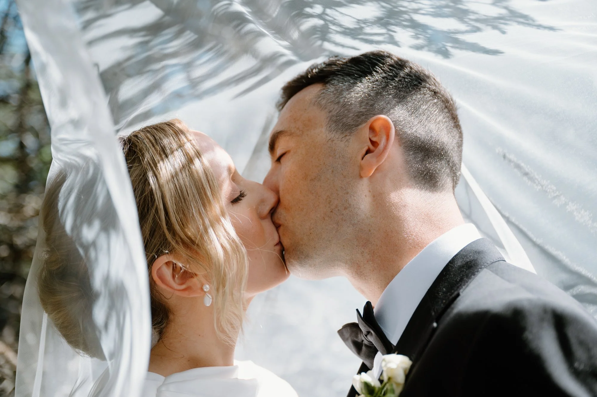 Editorial inspired portrait of a bride and groom kissing under the bridal veil at a destination wedding