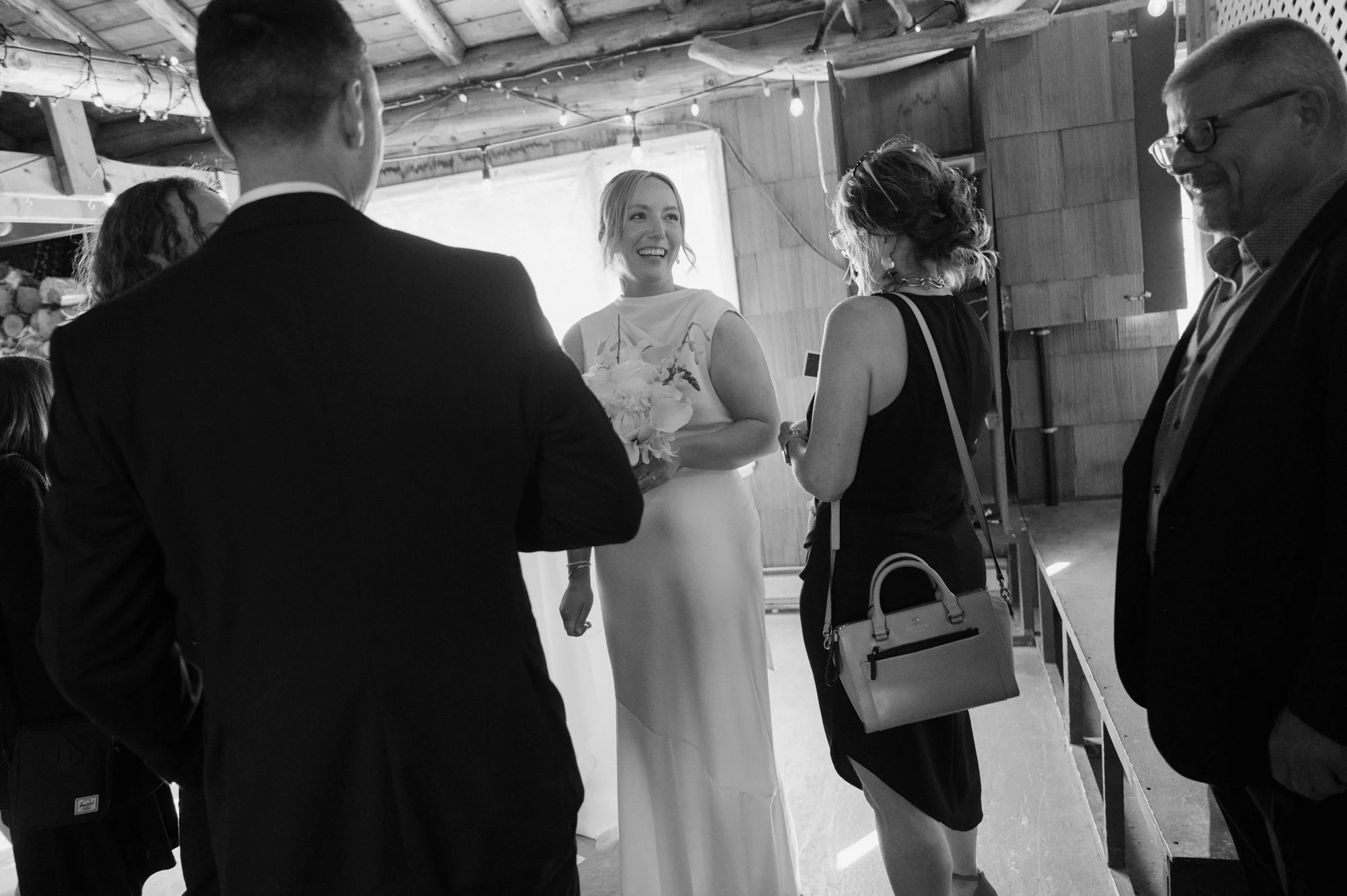 Black and white documentary candid of a bride interacting warmly with guests during her destination wedding reception