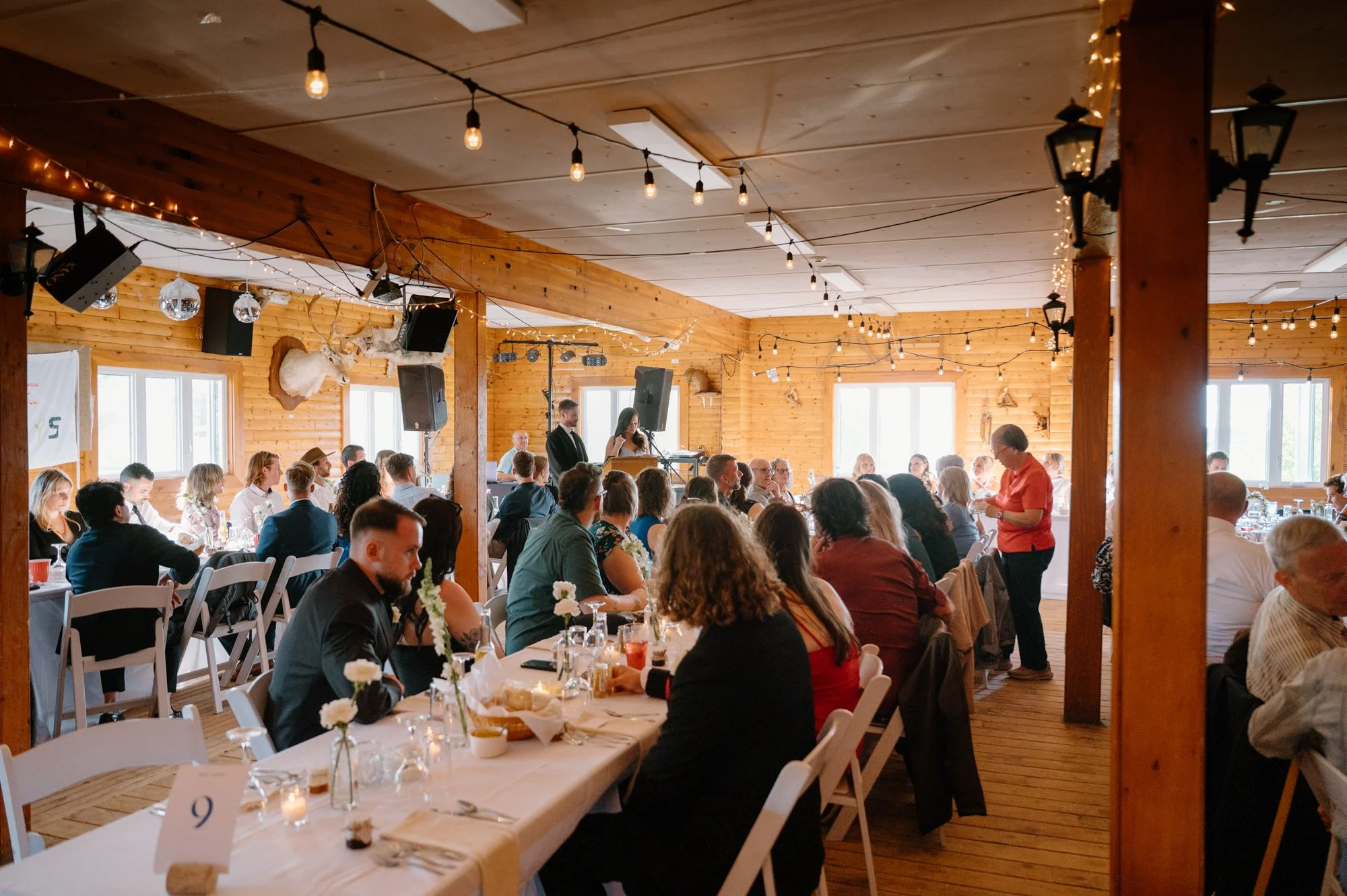 Wide room photo of guests gathered during the reception at a destination wedding ski lodge in Newfoundland
