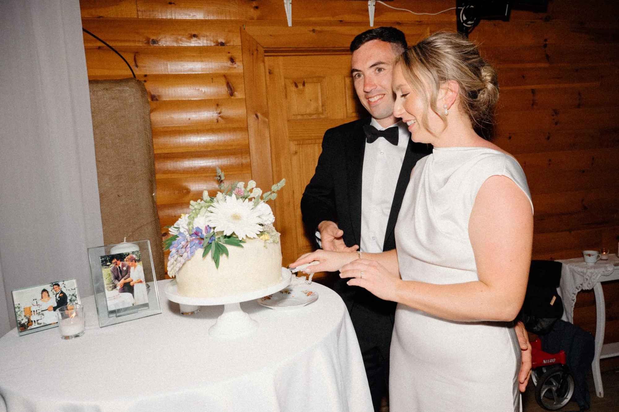 Film inspired flash photo of a bride and groom cutting their homemade wedding cake at a destination wedding reception