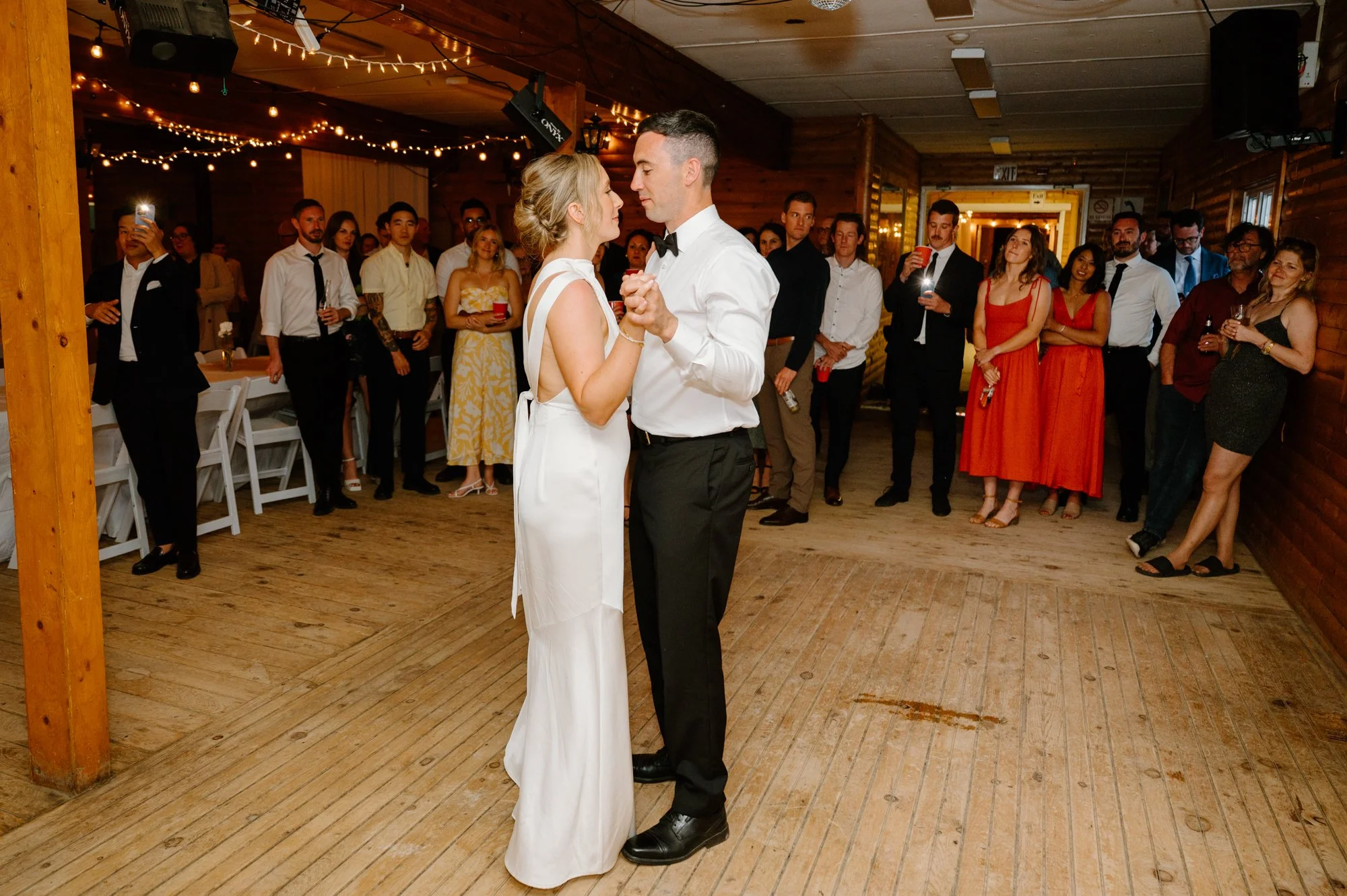 Bride and groom sharing their first dance surrounded by smiling guests at their destination wedding reception
