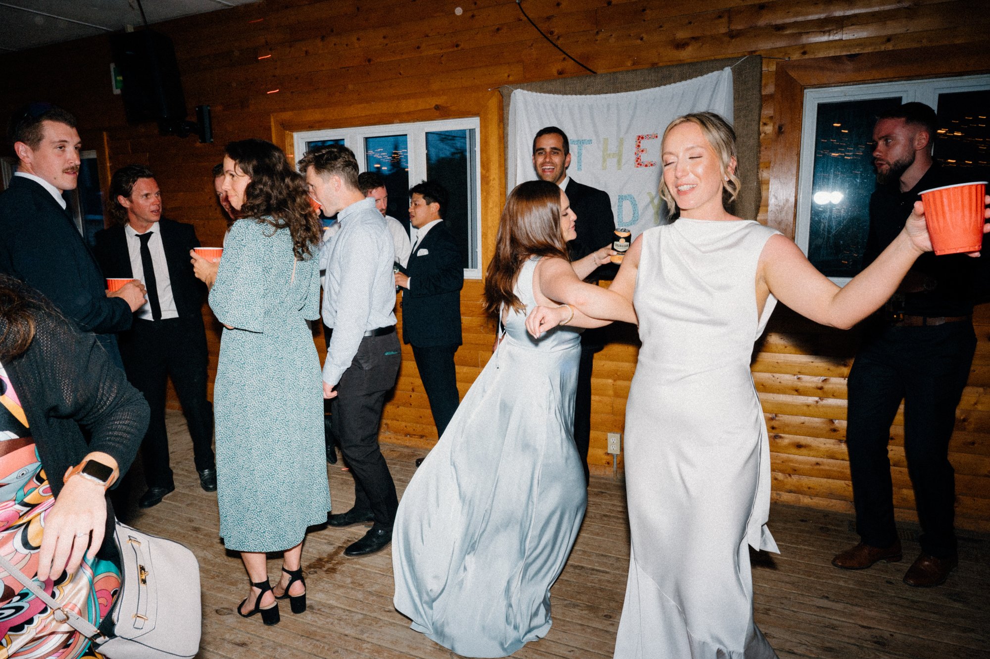 Candid photo of a bride dancing joyfully with guests during her destination wedding reception in Newfoundland