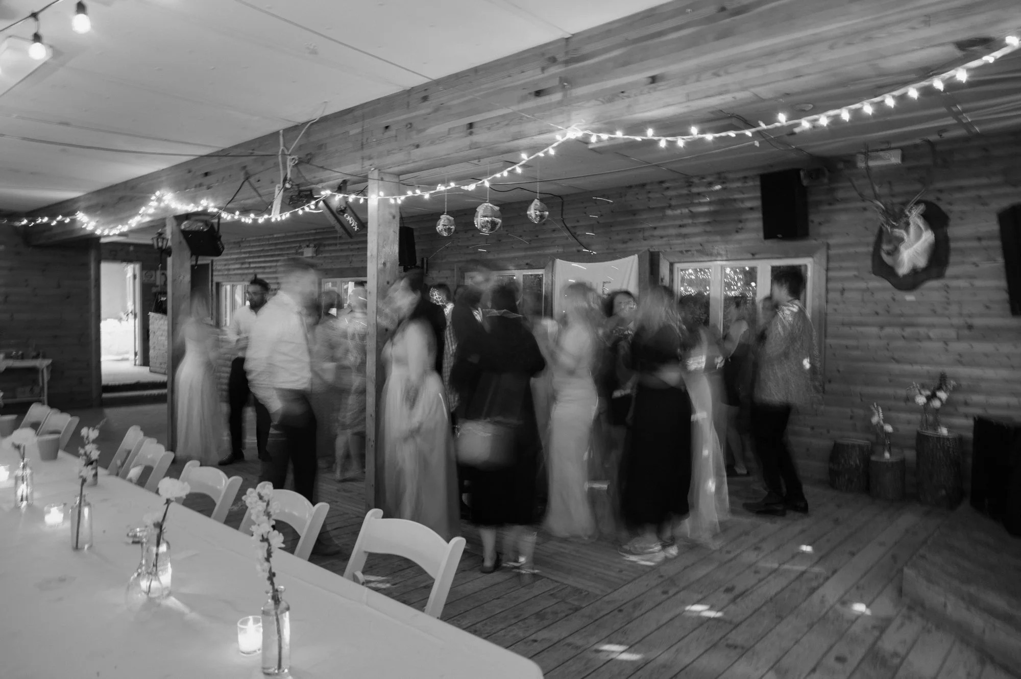 Film inspired black and white photo with motion blur of guests dancing at a destination wedding reception