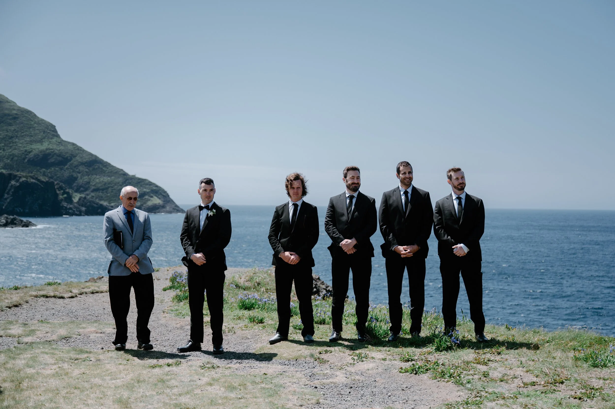 Candid photo of a groom and his groomsmen during an outdoor cliffside wedding ceremony in Newfoundland