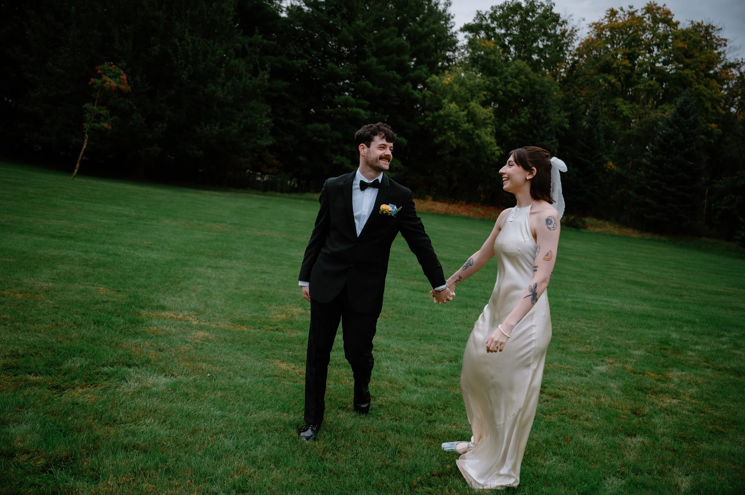 Bride and groom walking through an open field at Langdon Hall during their wedding reception