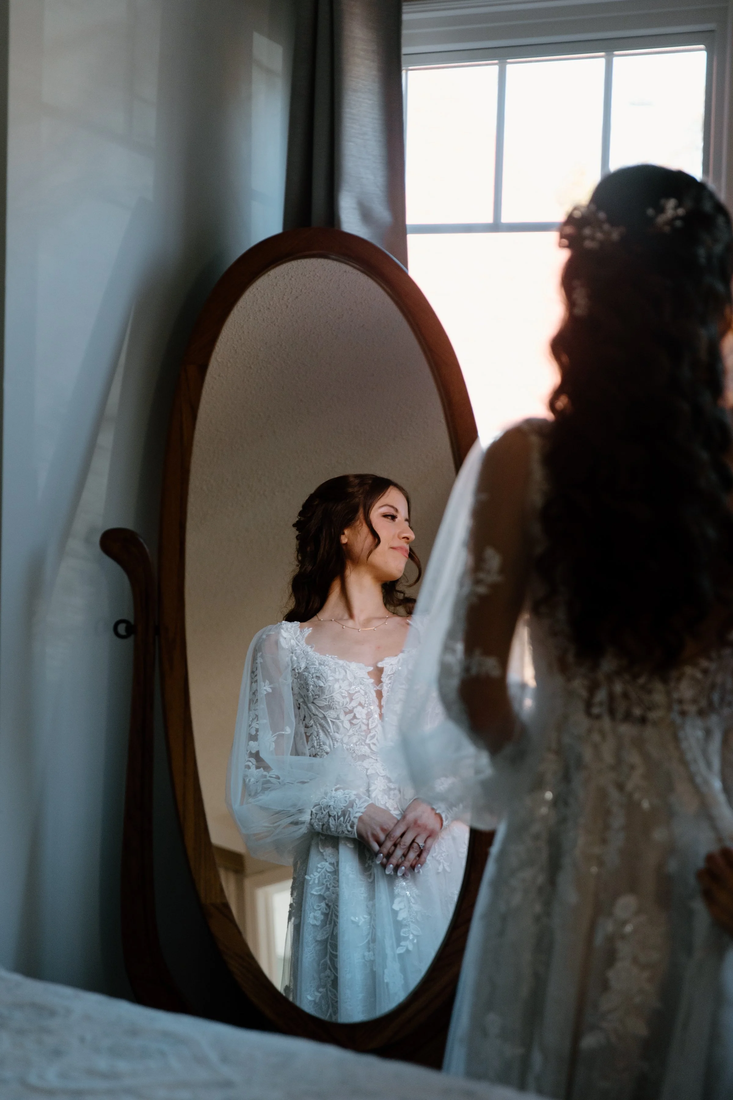 Editorial portrait of a bride looking at herself in her wedding dress, captured as a dramatic mirror reflection