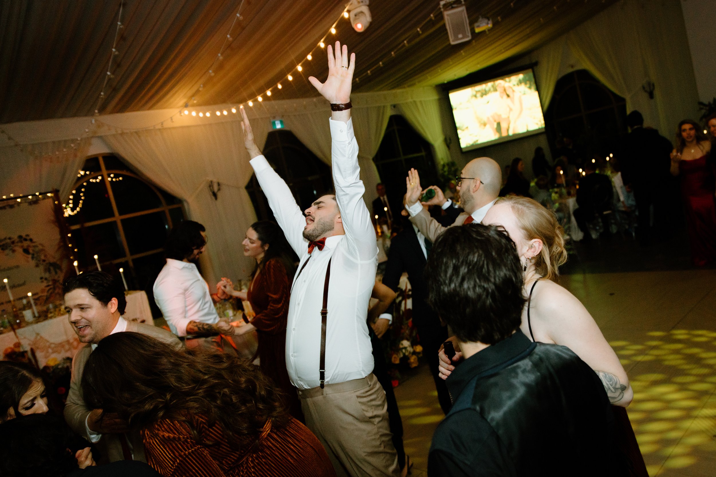 Candid photo of the groom dancing on the dancefloor surrounded by guests at his Caledon wedding reception