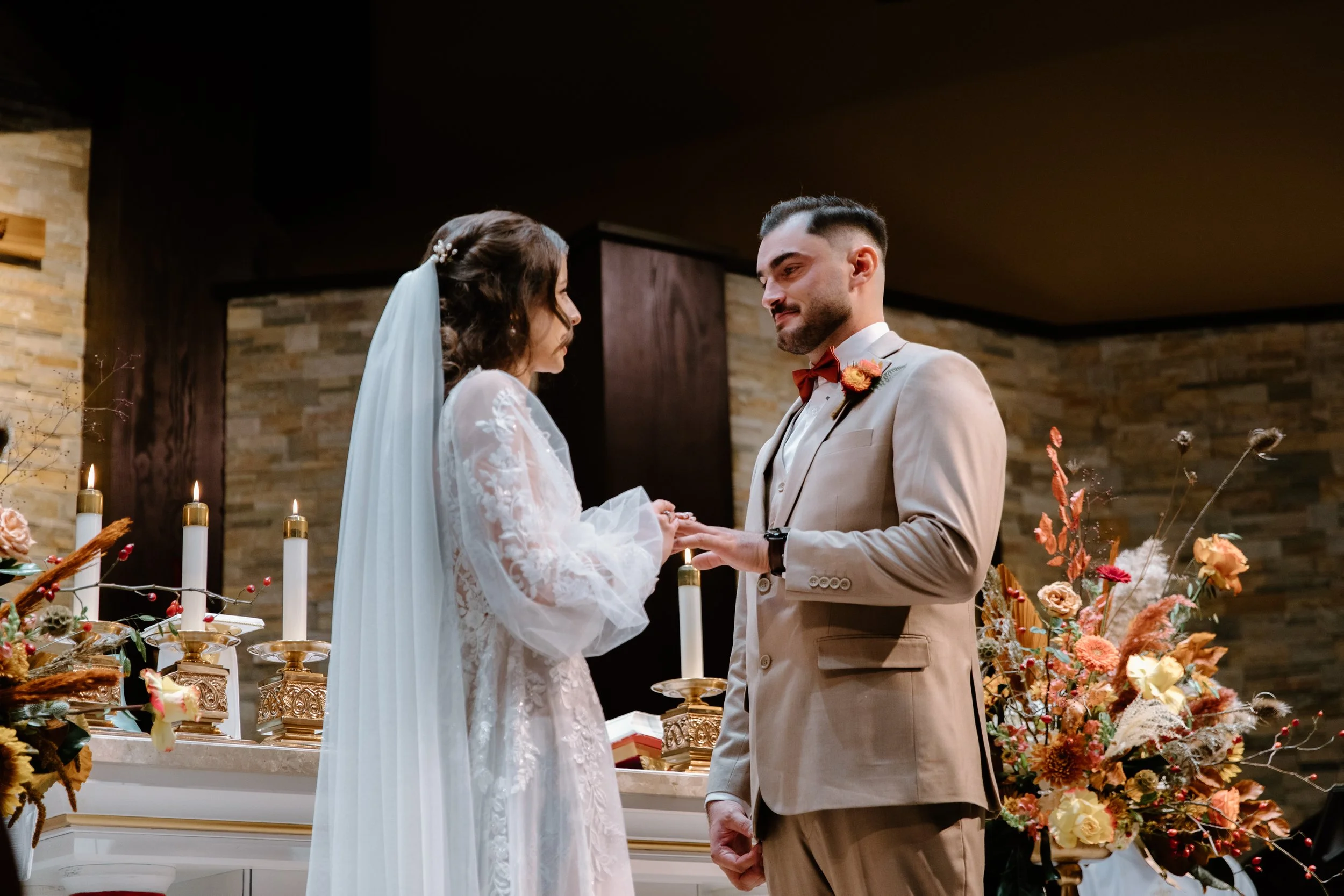 Detail photo of a bride placing a wedding ring on her groom's hand during their church ceremony in Toronto