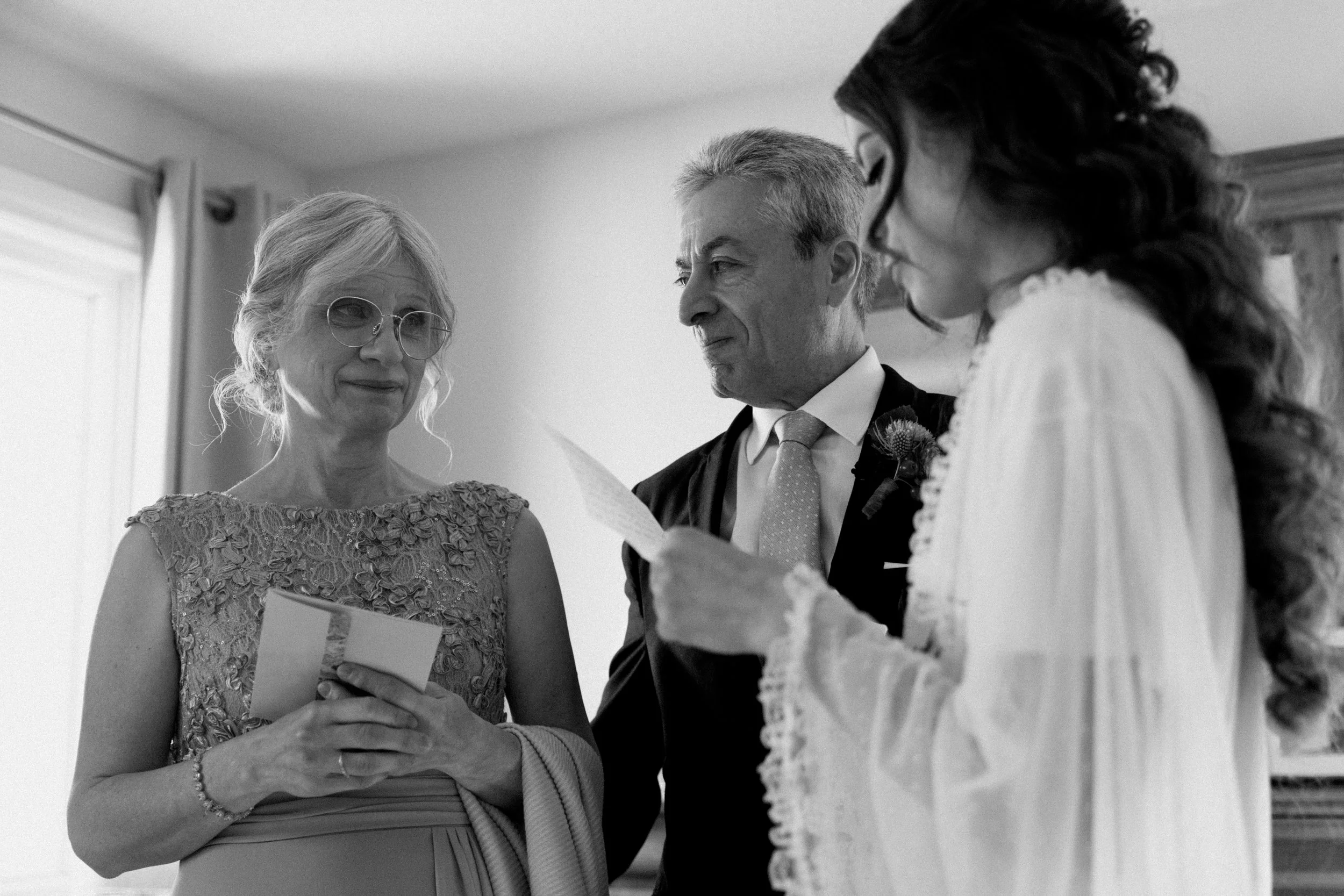 Emotional black and white photo of a bride and her parents while she reads a letter from them on her Toronto wedding morning