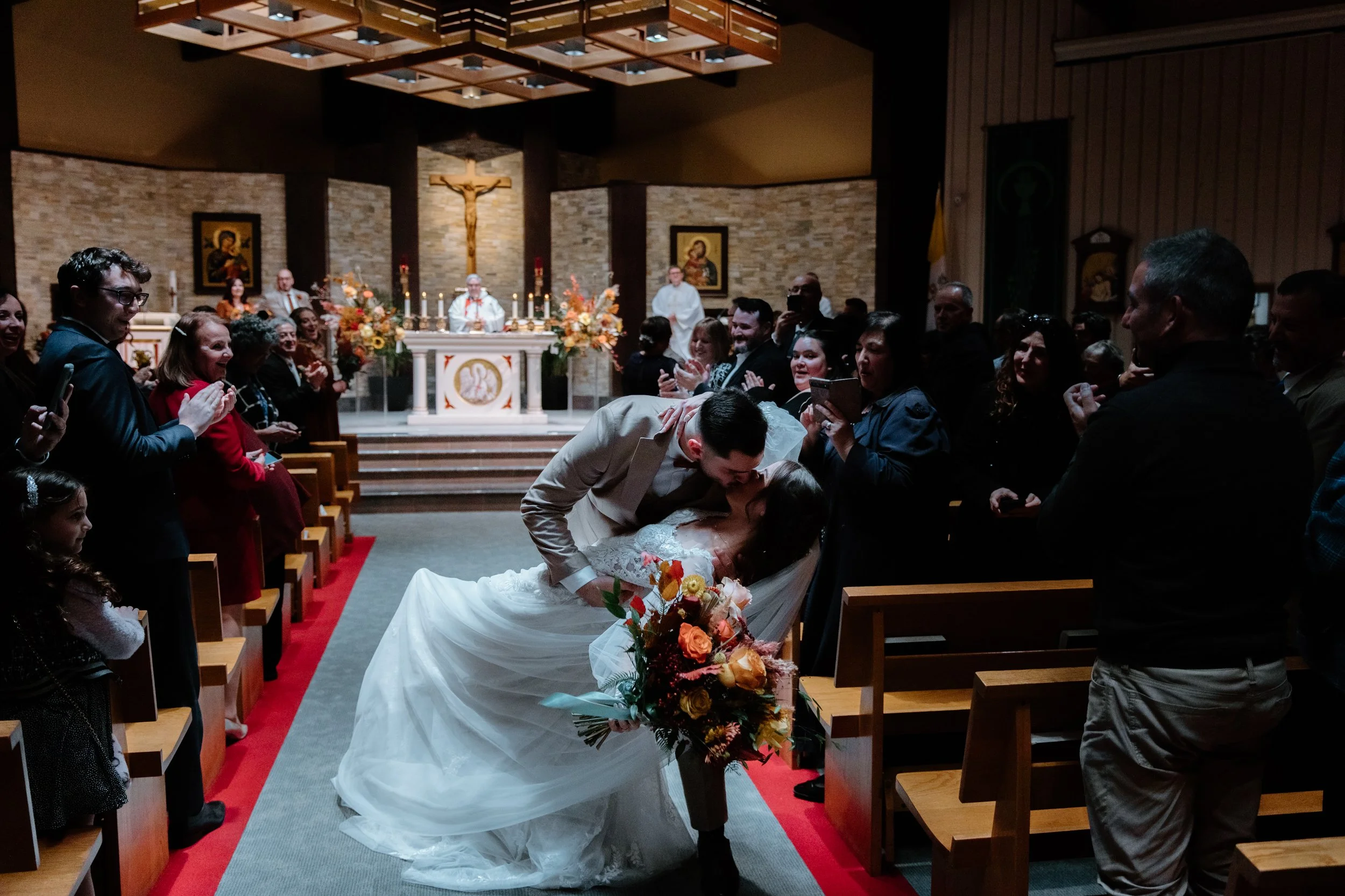 Candid photo of a couple kissing in the middle of the church aisle during their recessional at their Toronto wedding