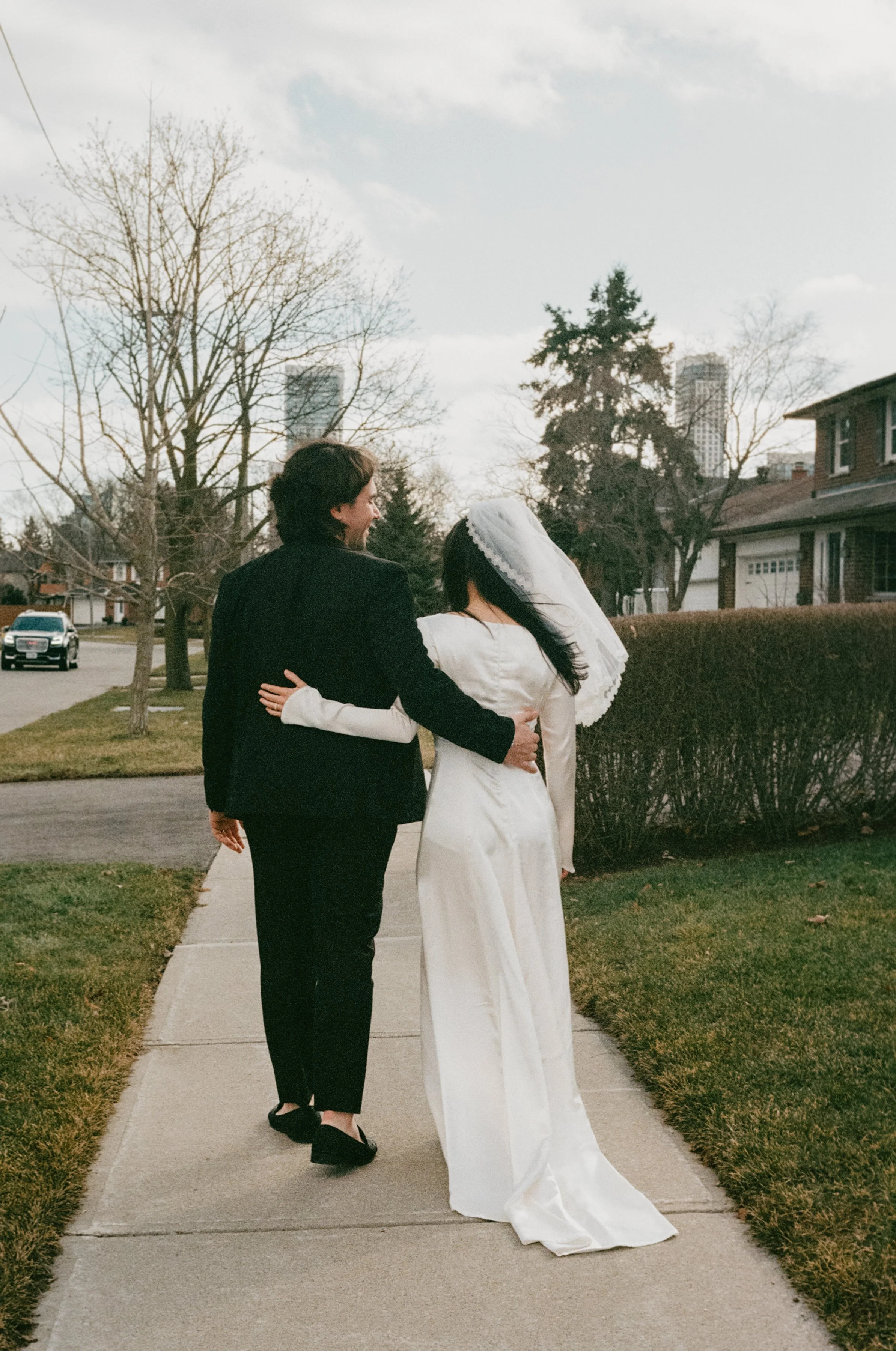 Film flash photography portrait of a bride and groom walking outside together after their at-home civil ceremony in Vancouver