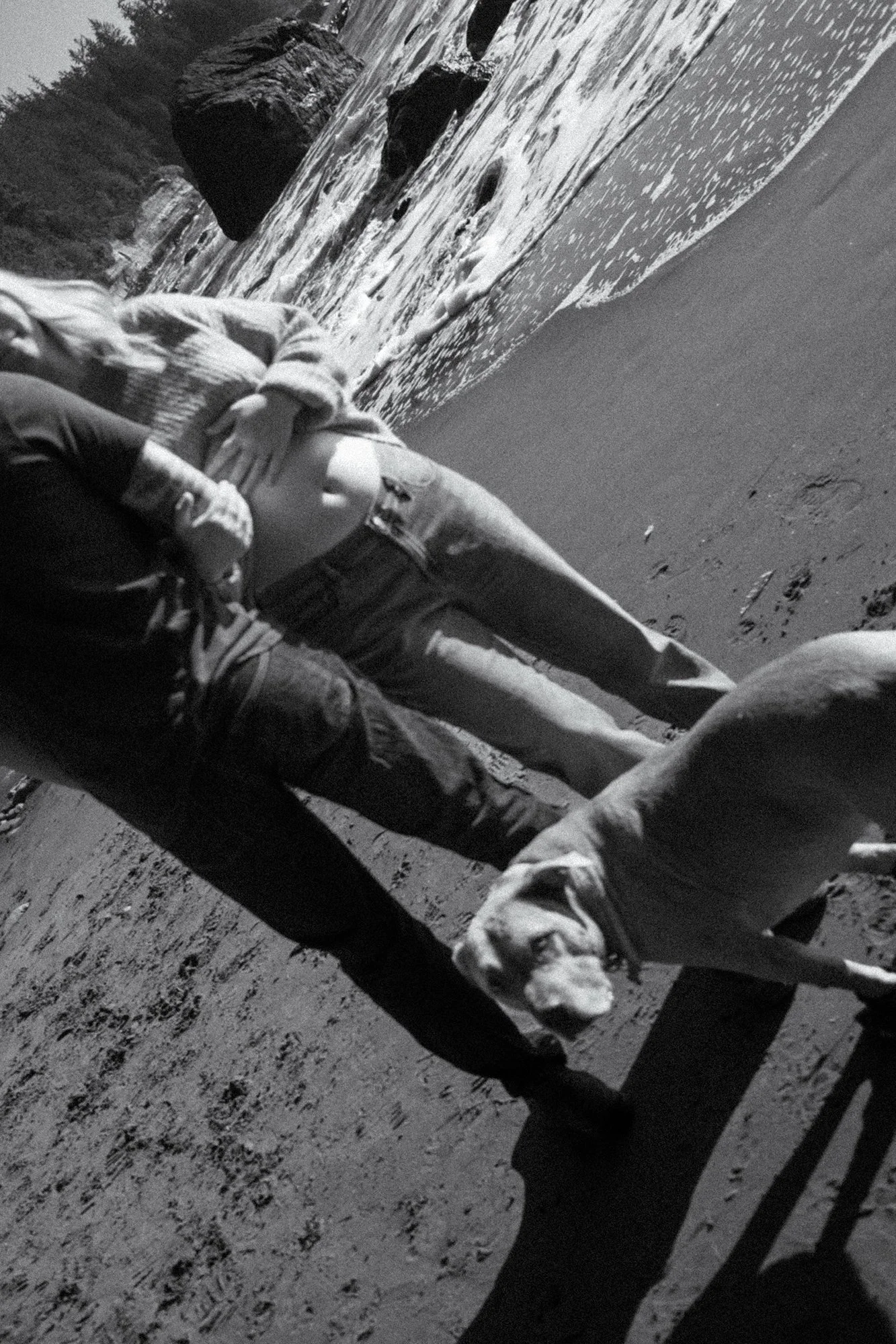 Soft and slightly out of focus black and white film photograph of a couple and their dog at the oceanfront near Tofino, BC during a maternity session