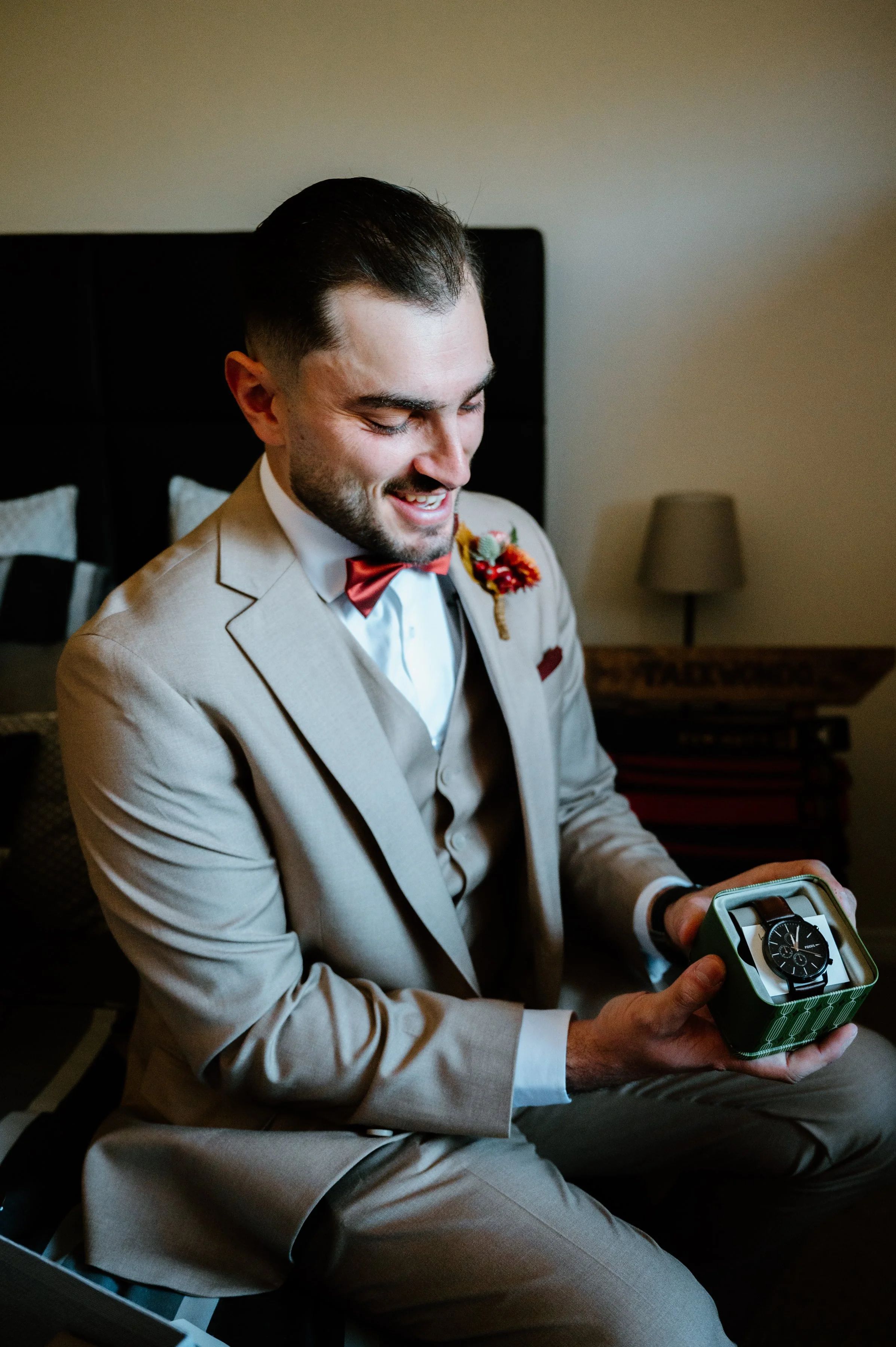 Candid photo of a groom happily opening a watch gift on his Toronto wedding morning